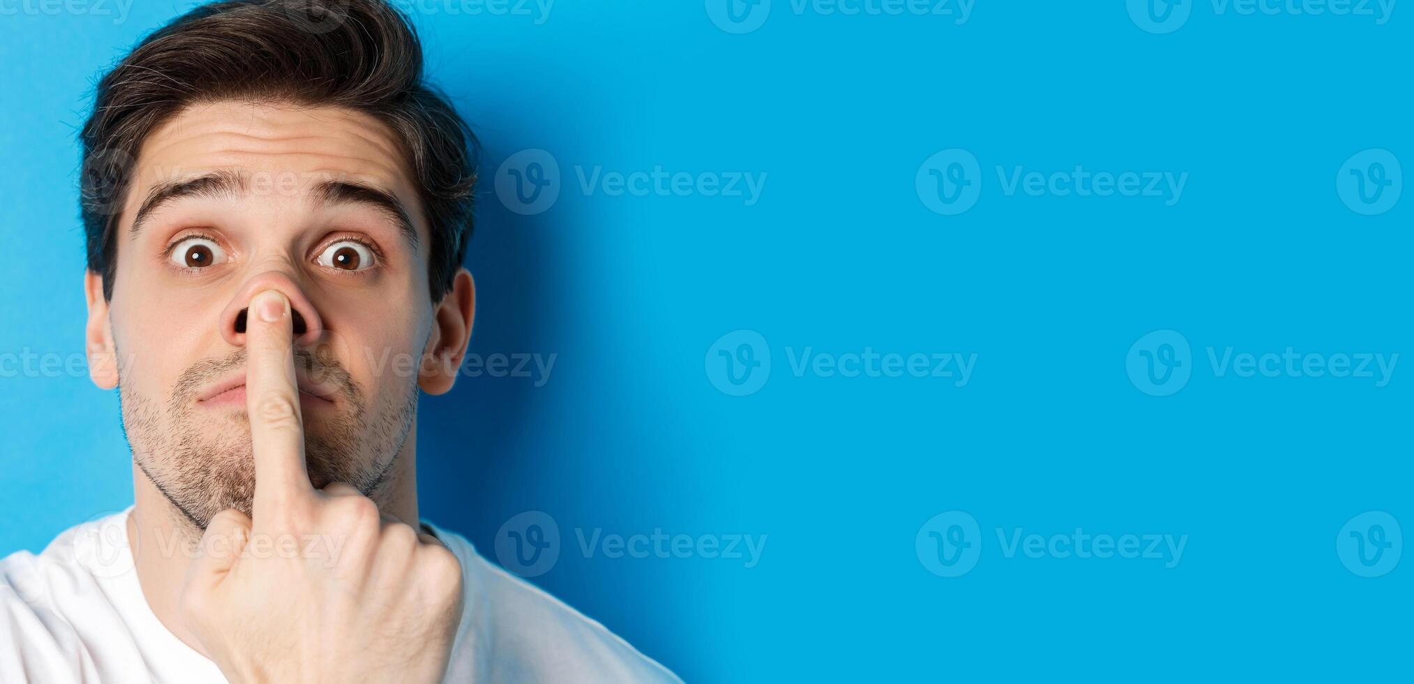 Headshot of caucasian guy making funny expressions, standing over blue background photo