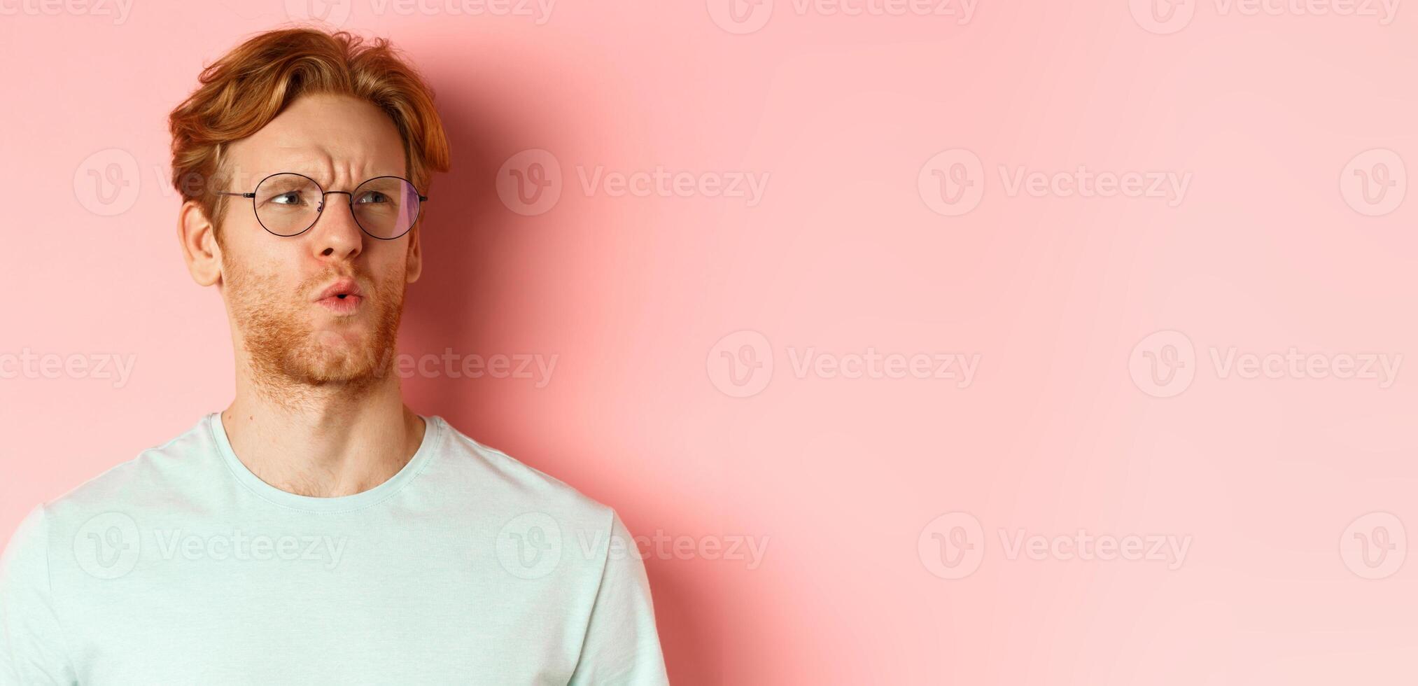 Ouch thats bad. Face of redhead man showing pity and feeling sorry for someone, frowning and looking with compassion, standing over pink background photo