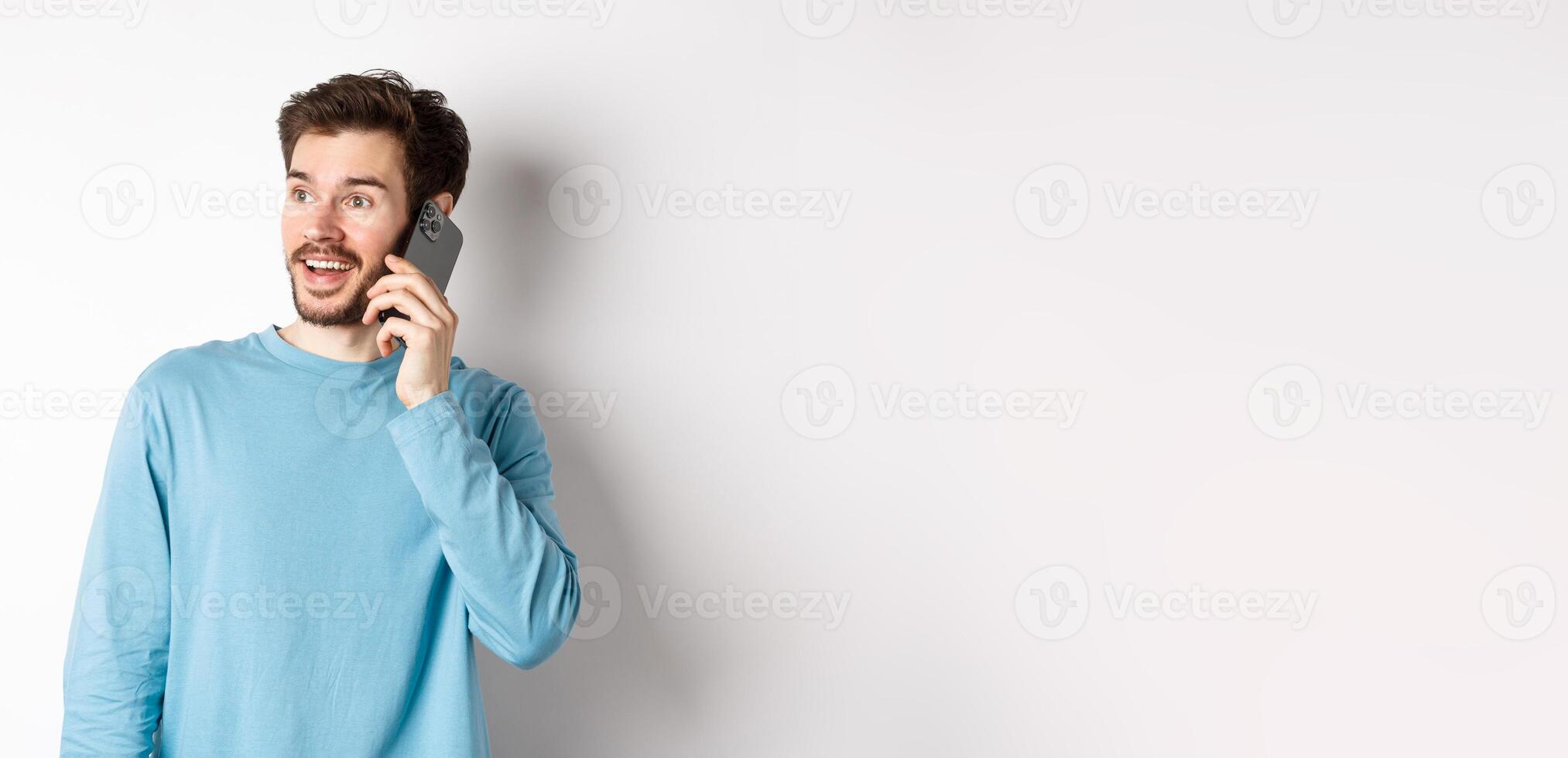 Technology concept. Cheerful man talking on mobile phone, having phone call and looking amused, standing over white background photo