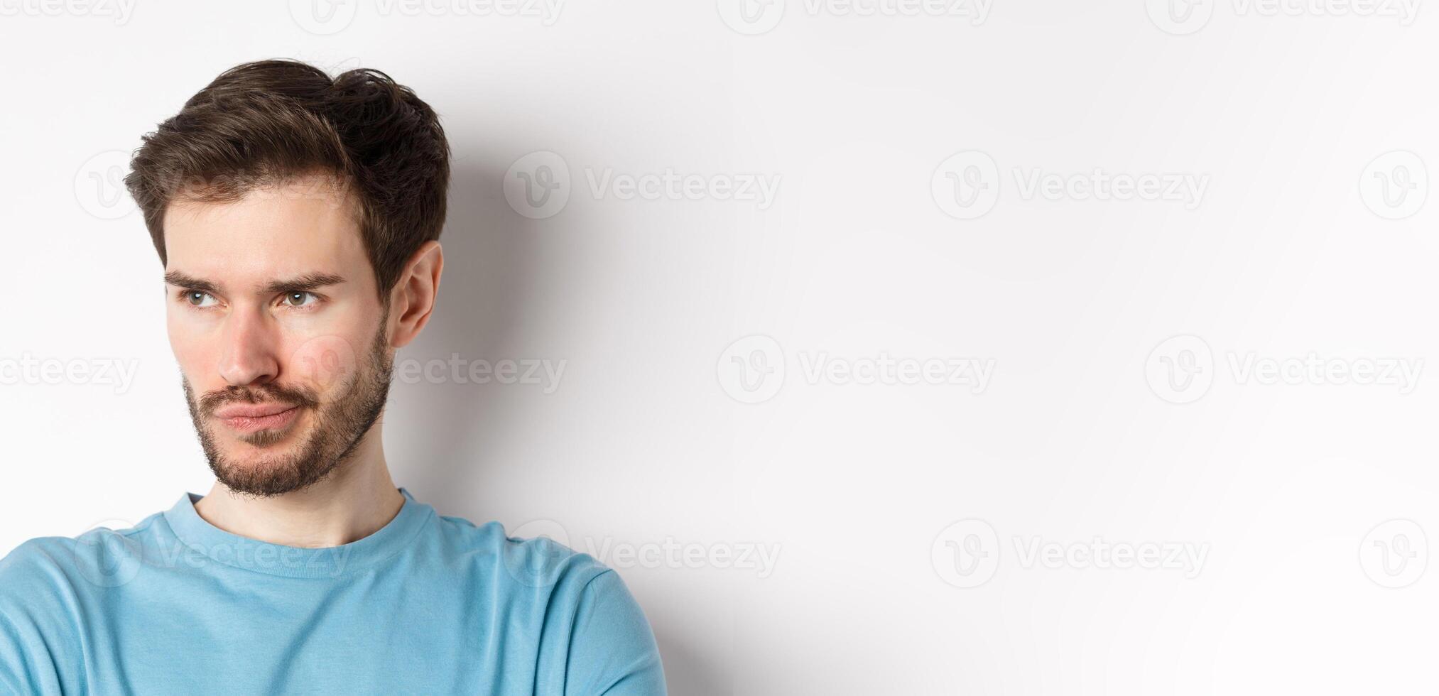Close-up of disappointed bearded man, sulking and looking left with pensive face, standing upset over white background photo