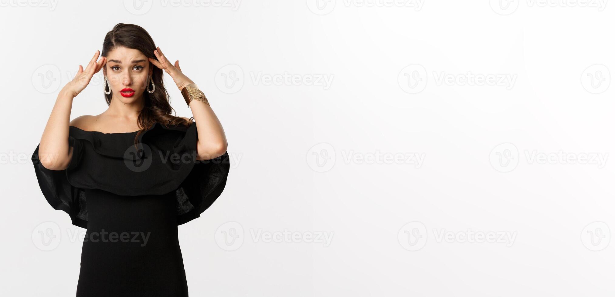 Fashion and beauty. Annoyed and tired woman in black dress, touching head and roll eyes bothered, standing distressed against white background photo