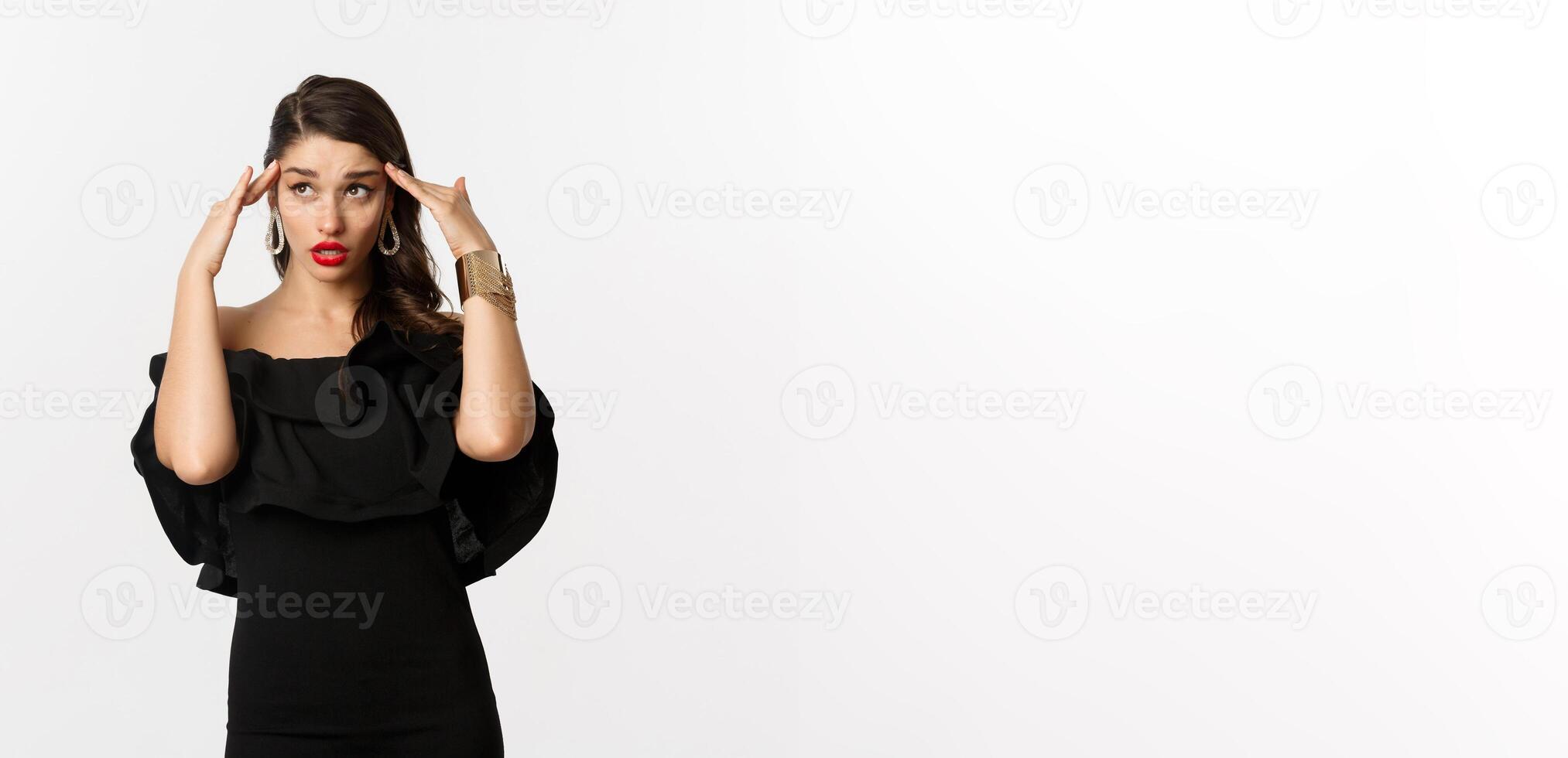 Fashion and beauty. Annoyed and tired woman in black dress, touching head and roll eyes bothered, standing distressed against white background photo