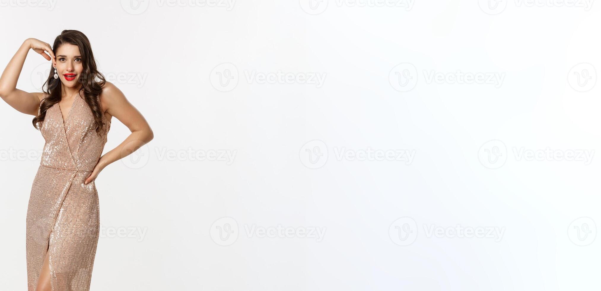 Party and celebration concept. Full-length of glamour woman posing near Christmas presents, wearing evening dress, standing over white background photo