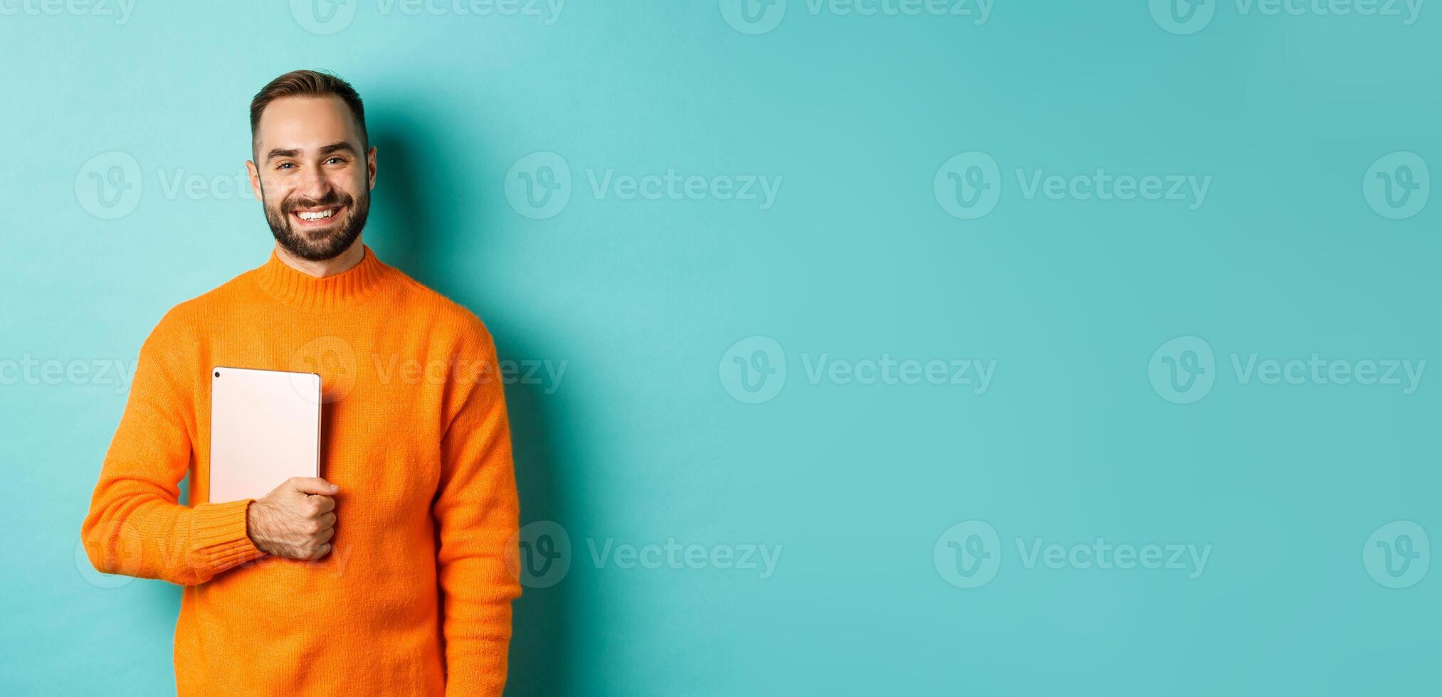 Handsome freelancer man holding laptop and smiling, standing happy over light blue background photo