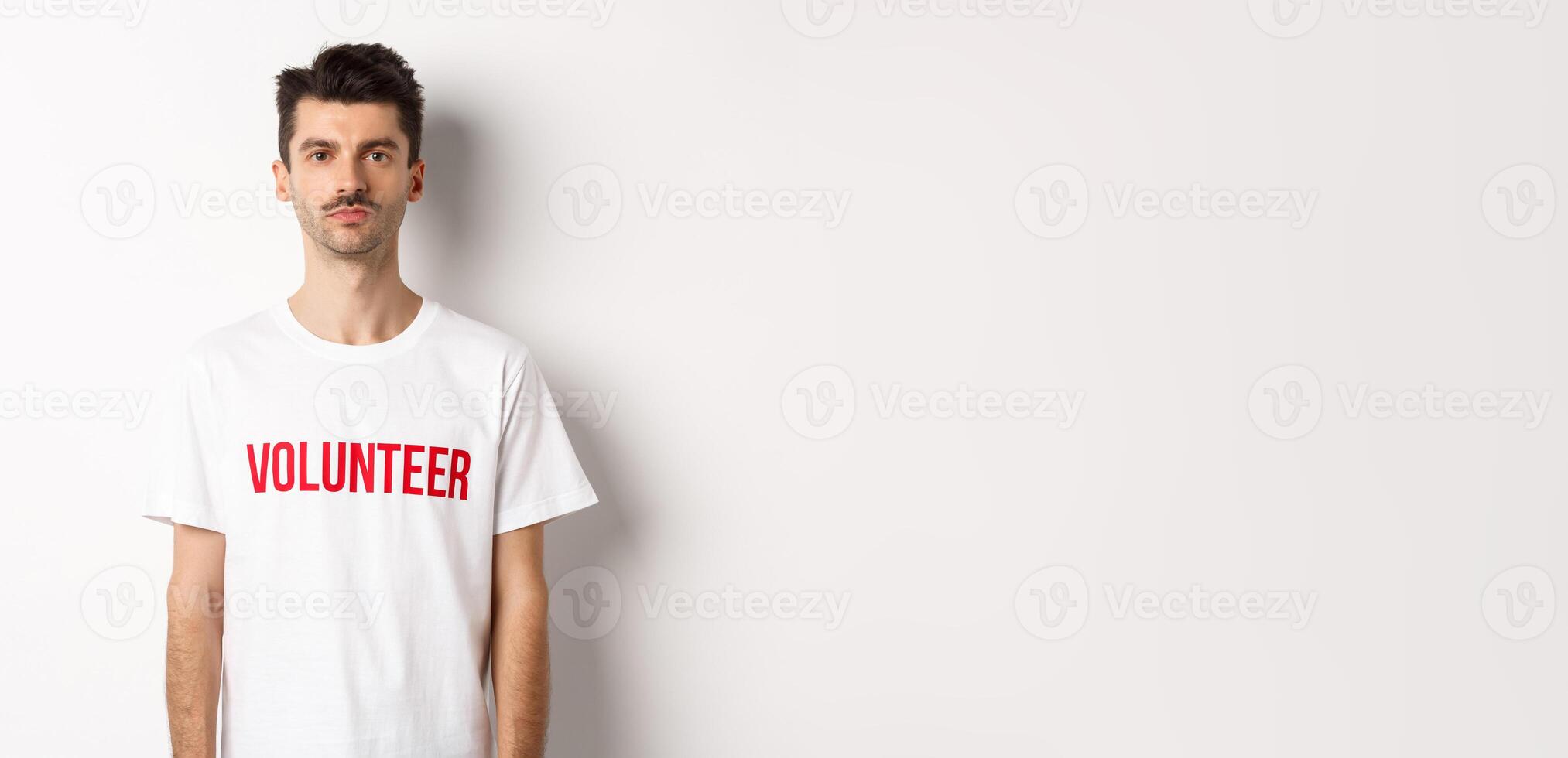 Serious young male volunteer in white t-shirt looking at camera, ready to help photo