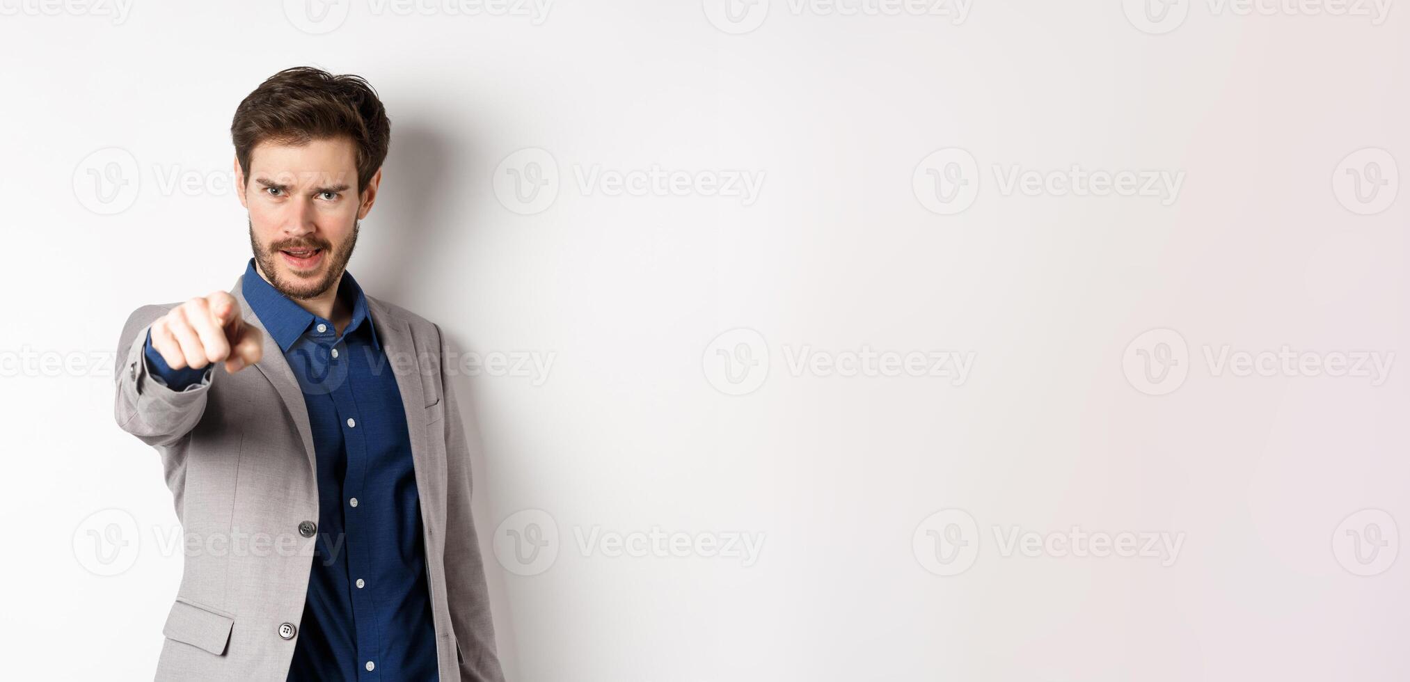 Confident and motivated businessman in suit need you, pointing finger at camera with encouraging face, choosing person, standing on white background photo