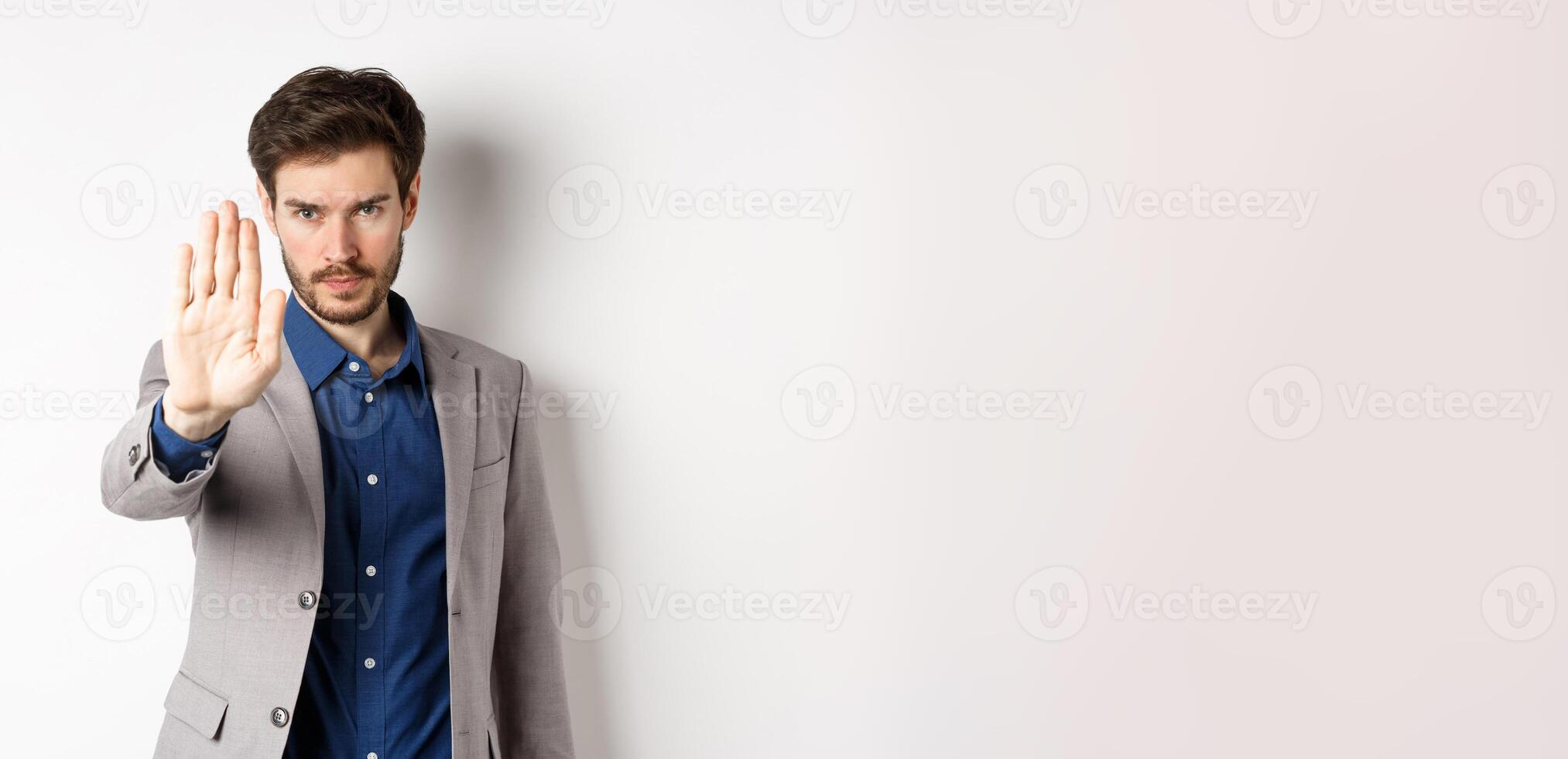 Hold right there. Serious businessman in suit stretch out hand and tell to stop, frowning and look confident, disapprove action, prohibit something bad, standing on white background photo