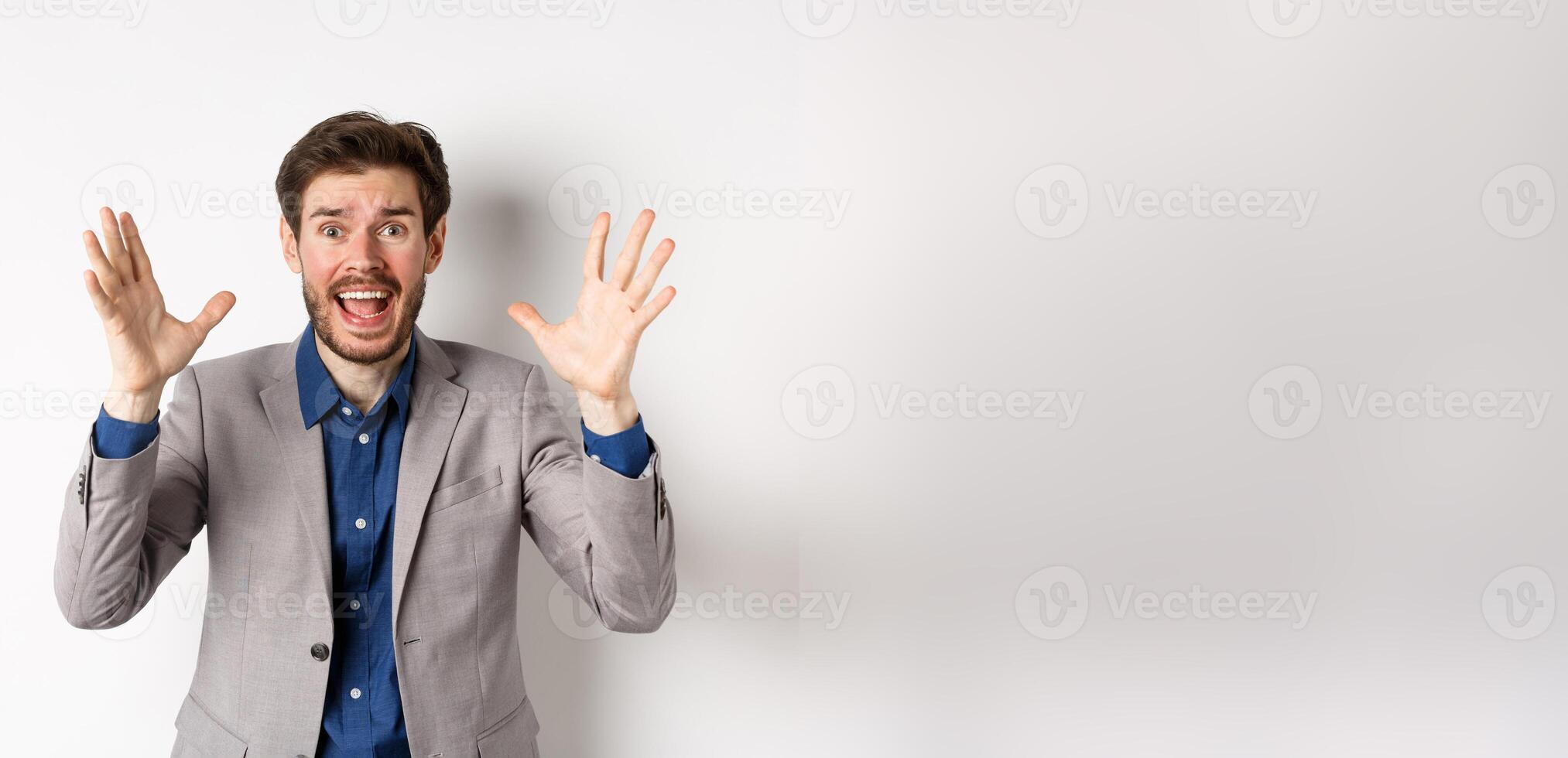 Businessman scream and shake hands in panic, look alarmed and anxious, shouting at camera, standing in suit on white background photo