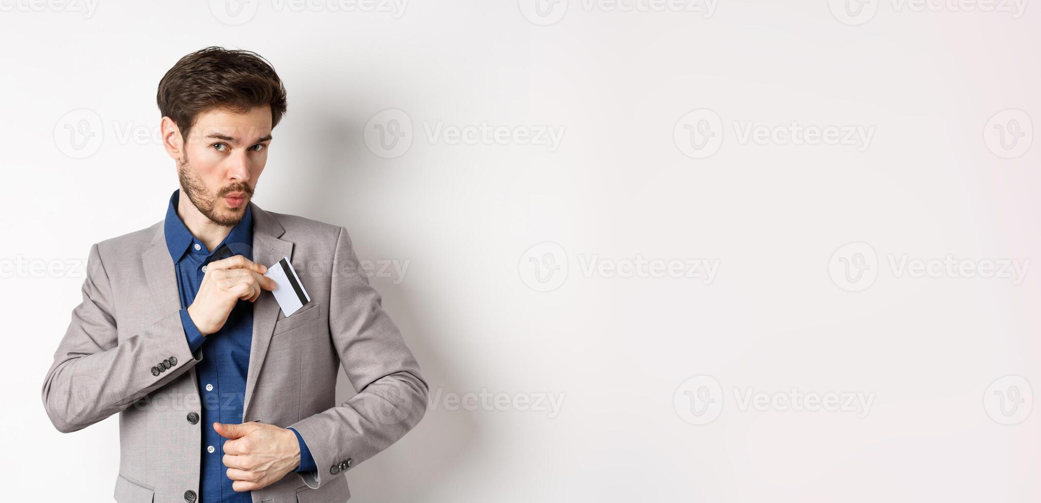 Businessman put credit card in suit pocket and whistling carefree, making shopping, standing on white background photo