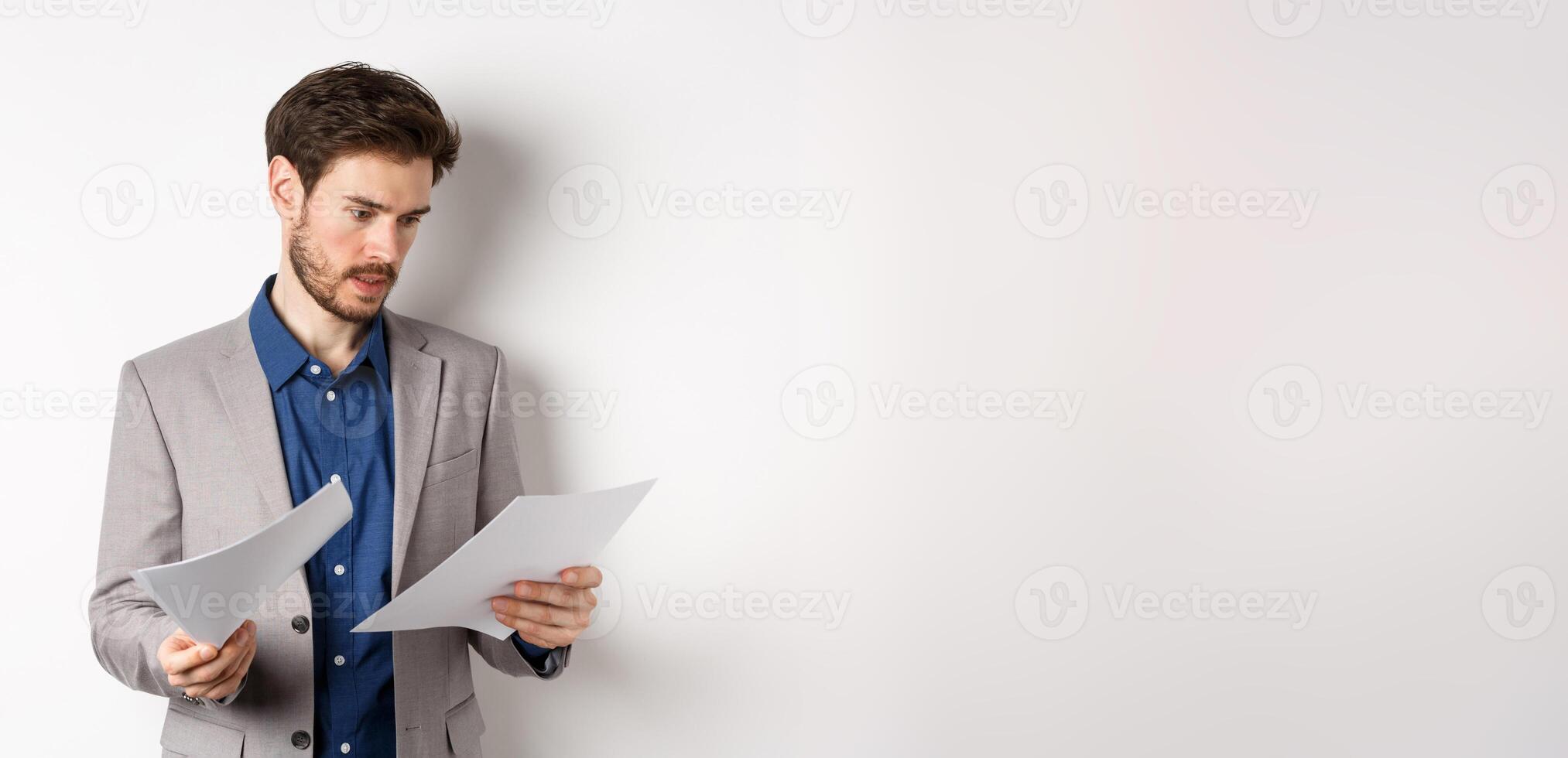 Businessman in suit looking through papers, reading documents at work, standing busy on white background photo