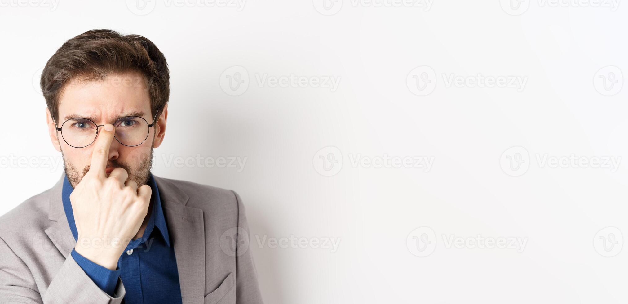 Serious boss in suit frowning, put on glasses and looking suspicious at camera, white background photo