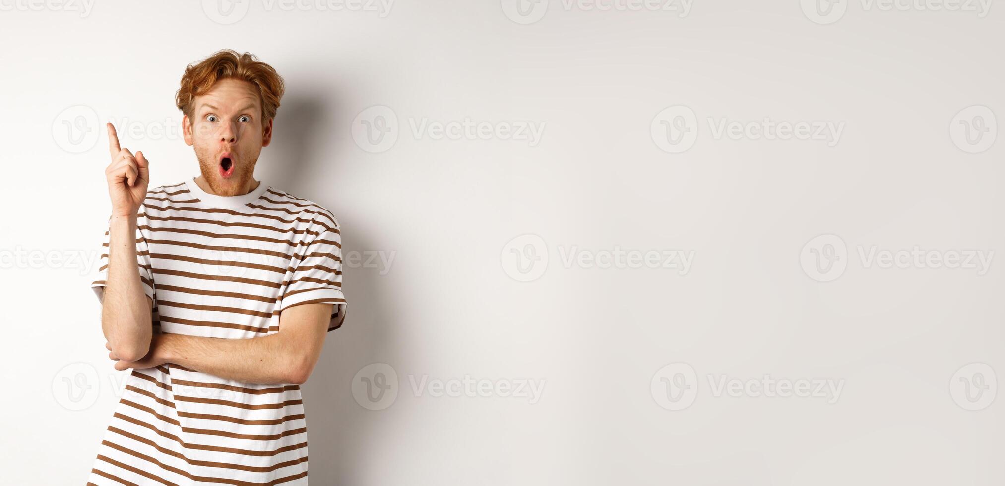 Excited redhead man having revalation, raising finger in eureka sign and saying idea, standing over white background photo