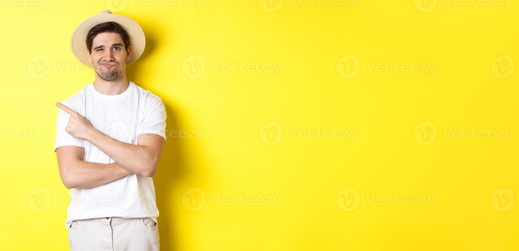 Concept of tourism and lifestyle. Skeptical guy tourist complaining, pointing finger left at something bad, looking displeased, yellow background photo