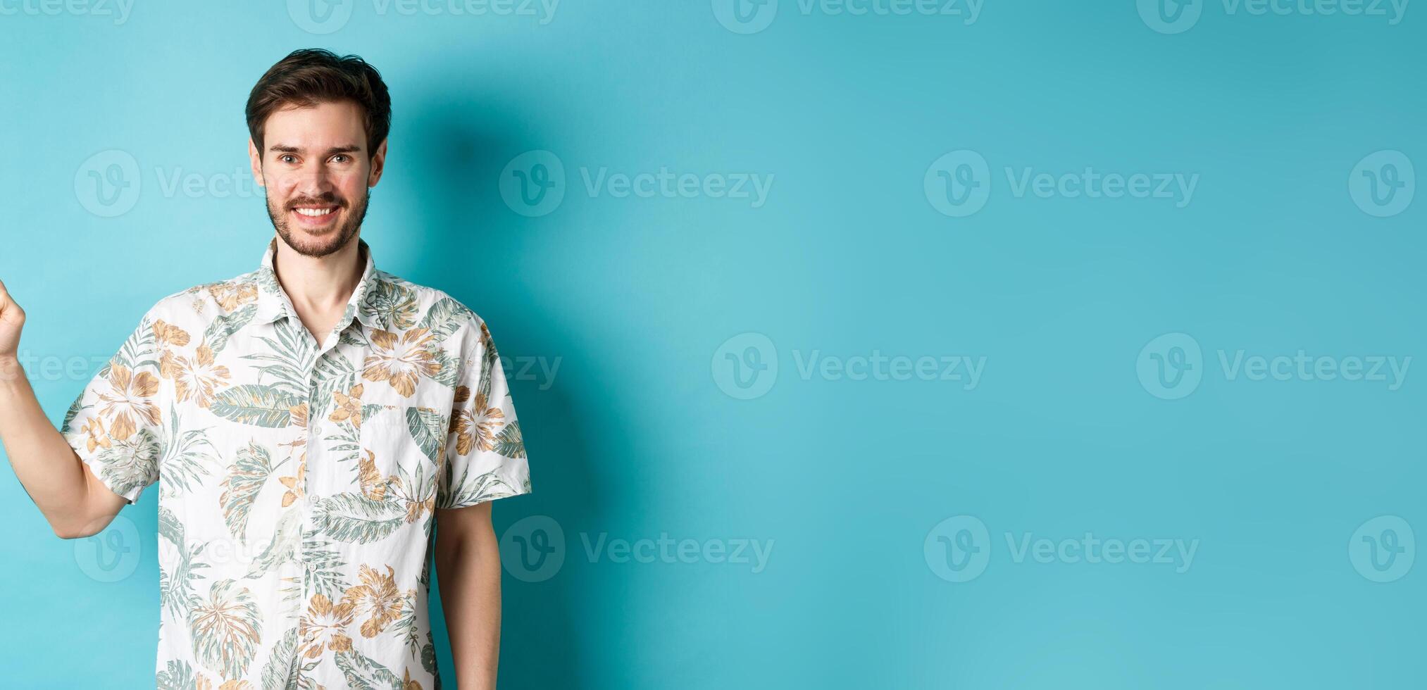 Smiling tourist in hawaiian shirt pointing finger at empty space, showing logo. Concept of vacation and travelling photo