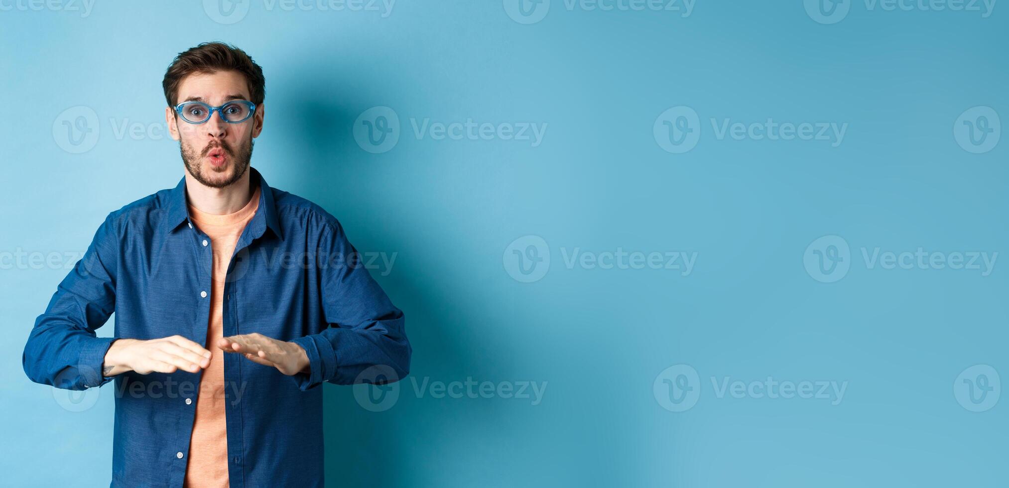 Funny guy trying sunglasses at eyewear store, dancing and having fun, standing on blue background photo