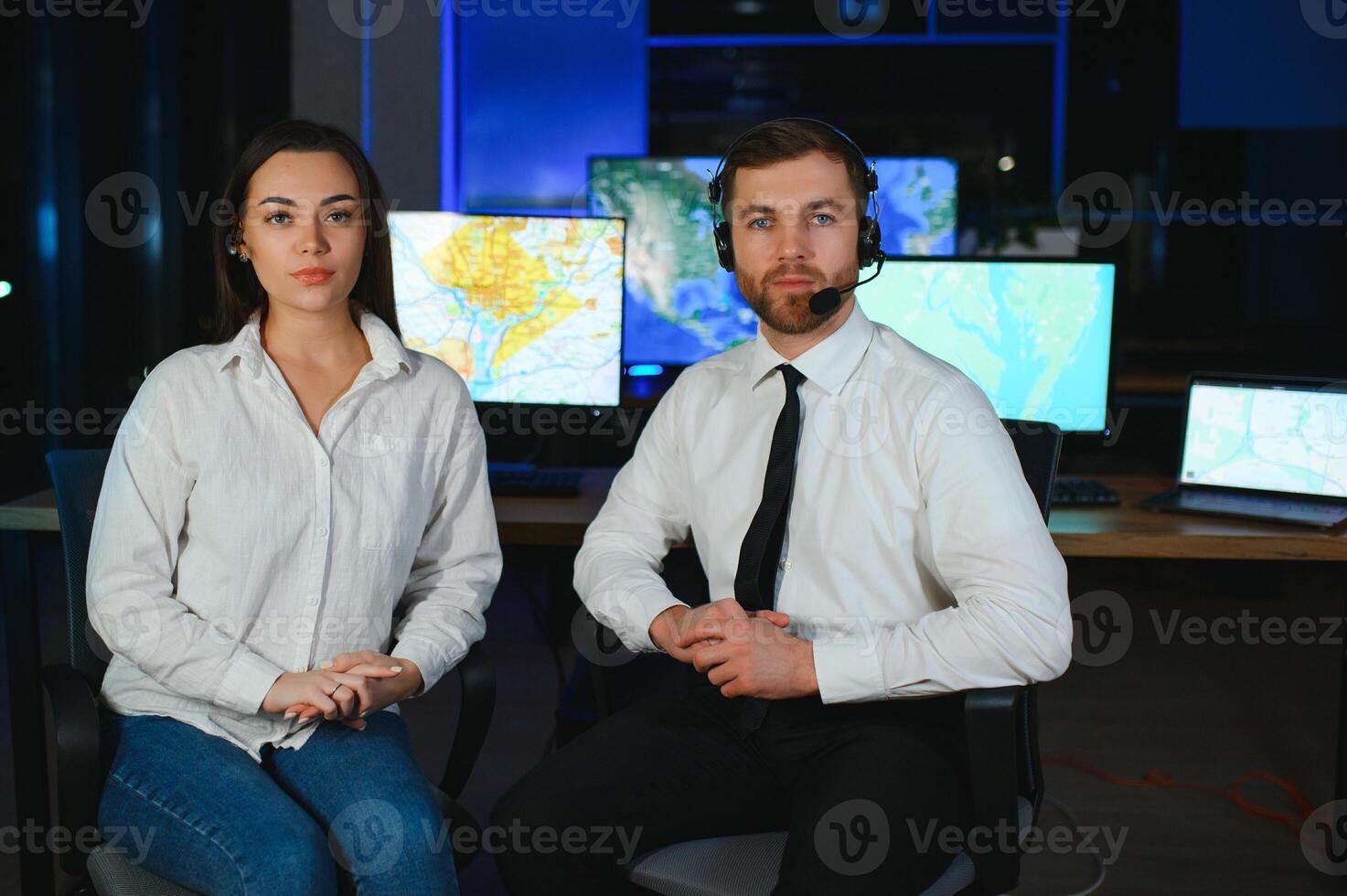 In Monitoring Room Technical Support Specialist Speaks into Headset. His Colleagues are Working in the Background photo