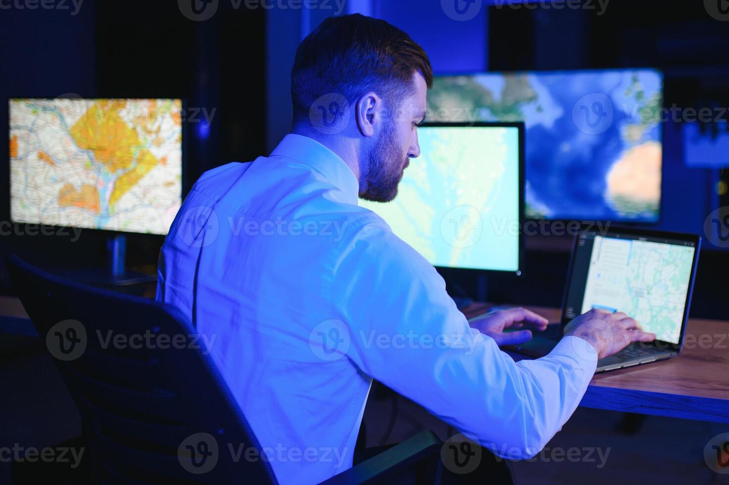 Male Data Scientist Works on Personal Computer Control and Monitoring Room. Map Surveillance of People Walking on City Streets photo