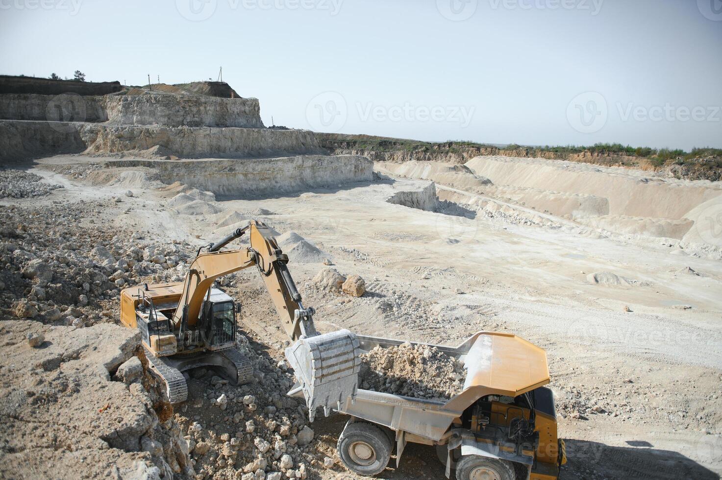 Large quarry dump truck. Big yellow mining truck at work site. Loading stone into body truck photo