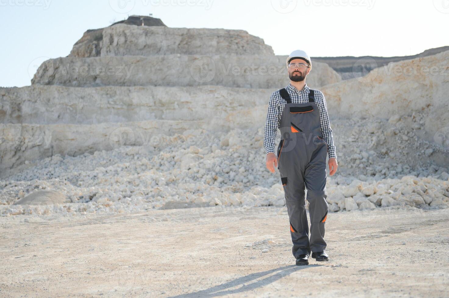 Worker in hardhat standing in stone quarry photo