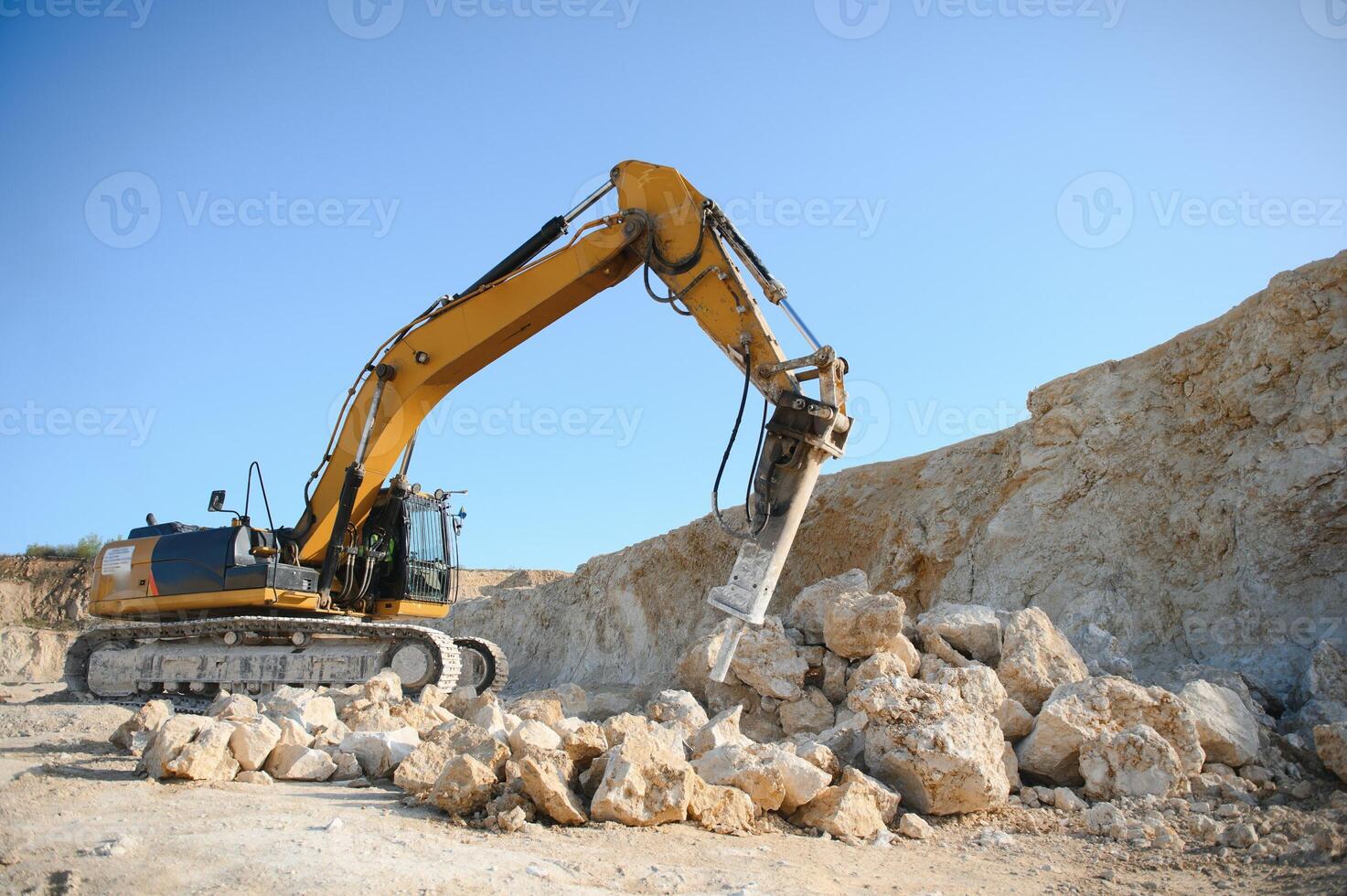 Hydraulic breaker hammer in a quarry for limestone mining with an excavator photo