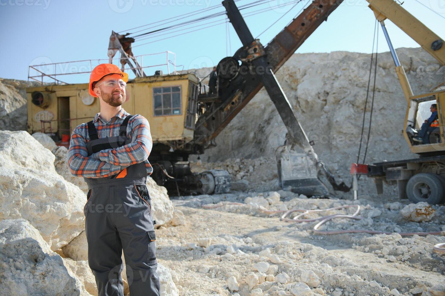 Worker in hardhat standing in stone quarry photo
