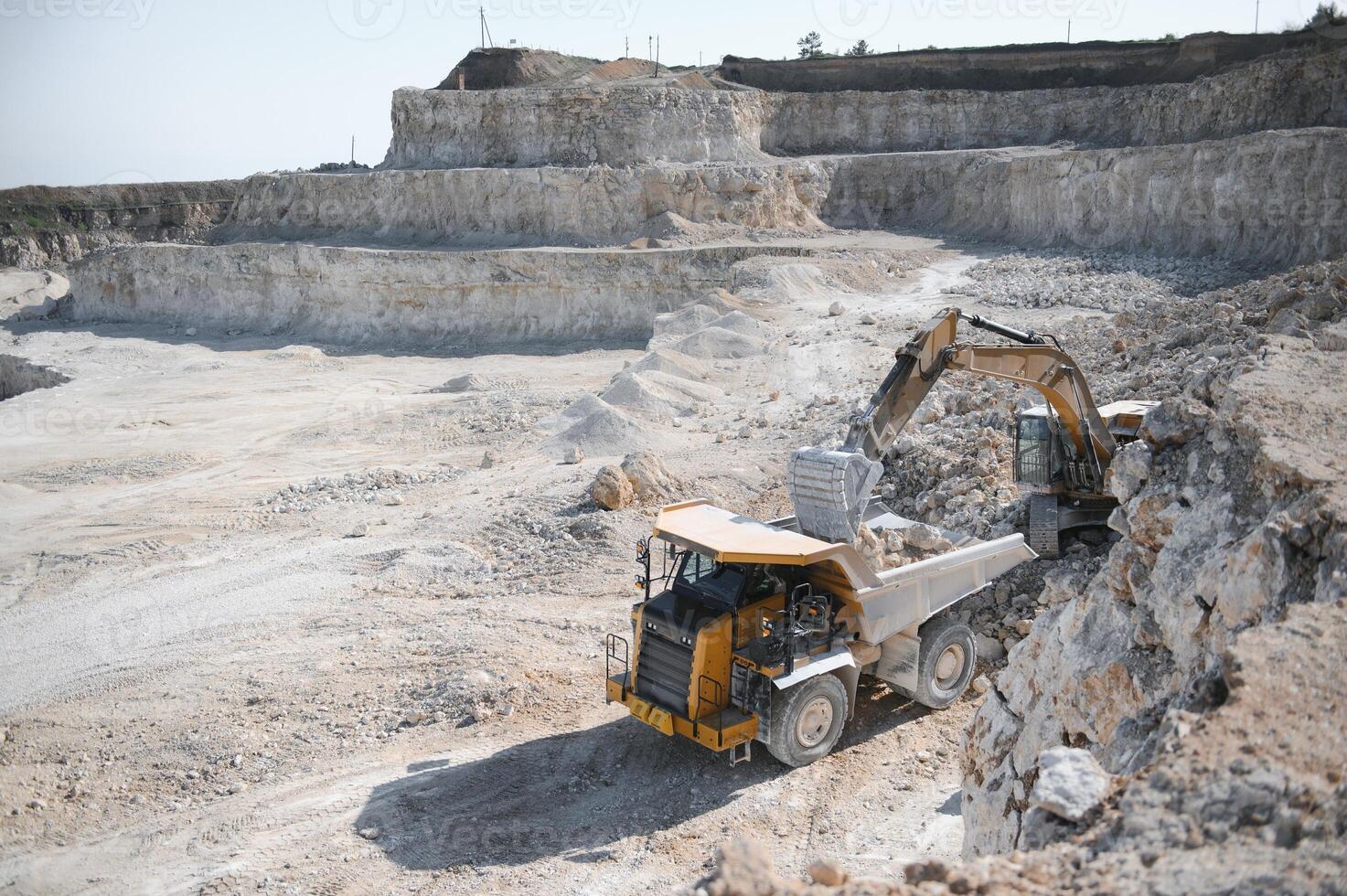 Heavy mining truck and excavator, close-up, against the background of the panorama of a limestone quarry photo