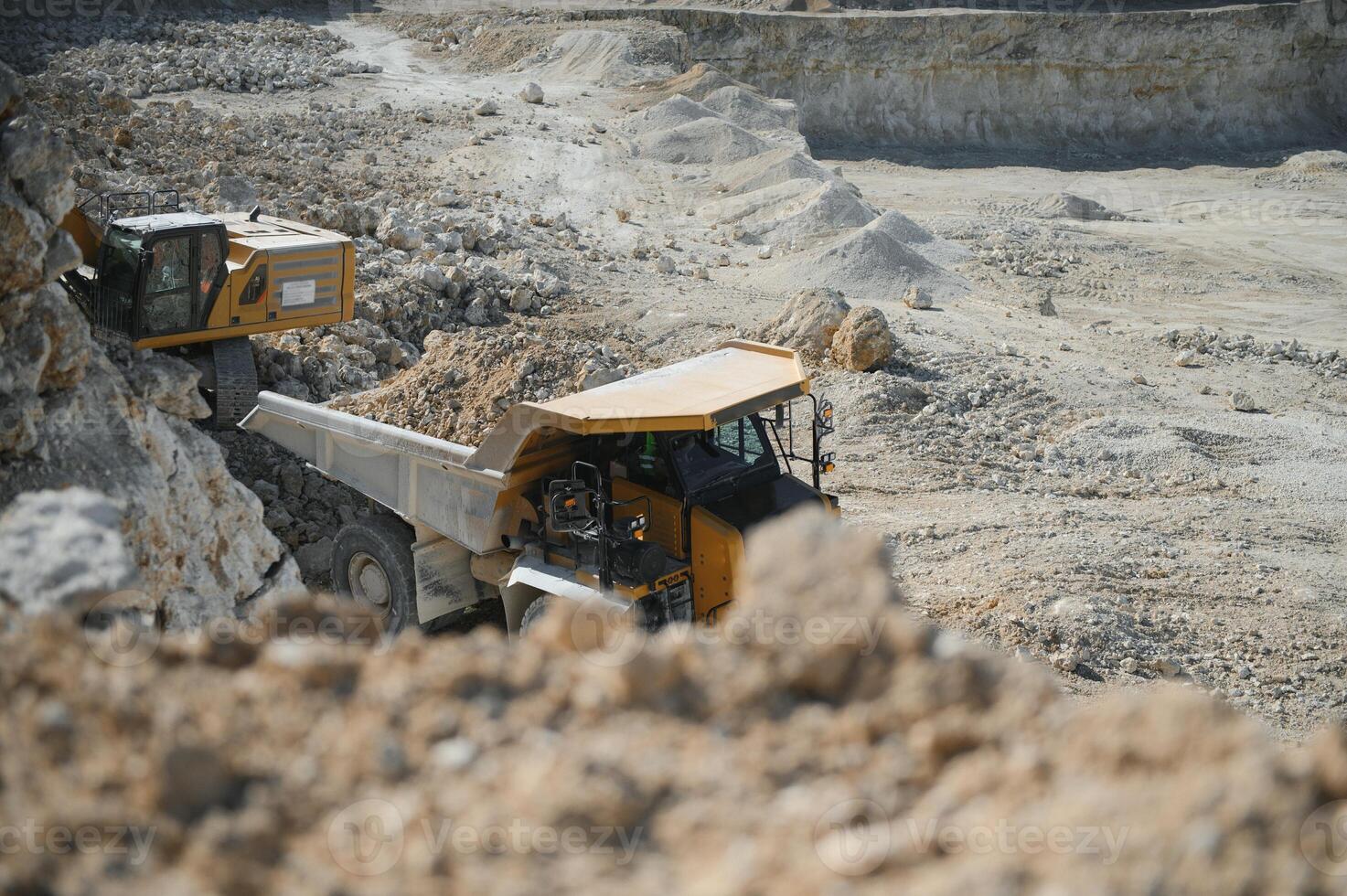 Large quarry dump truck. Big yellow mining truck at work site. Loading stone into body truck photo