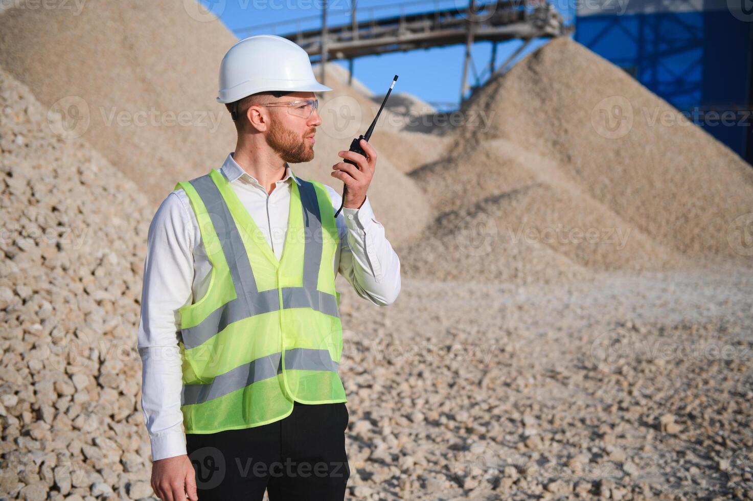 A worker in a helmet stands at a stone crushing plant photo