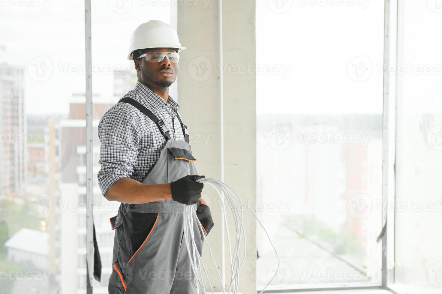 An African electrician stands on a construction site with a cable in his hands photo