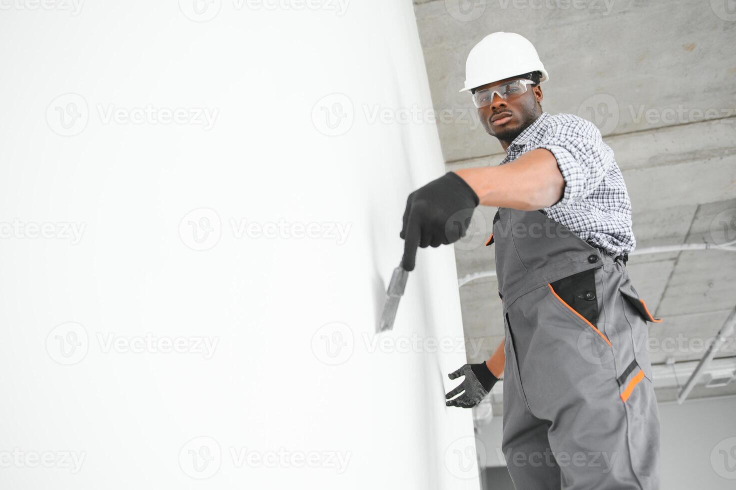 business, building, and people concept. african builder in hardhats with plastering tools indoors photo