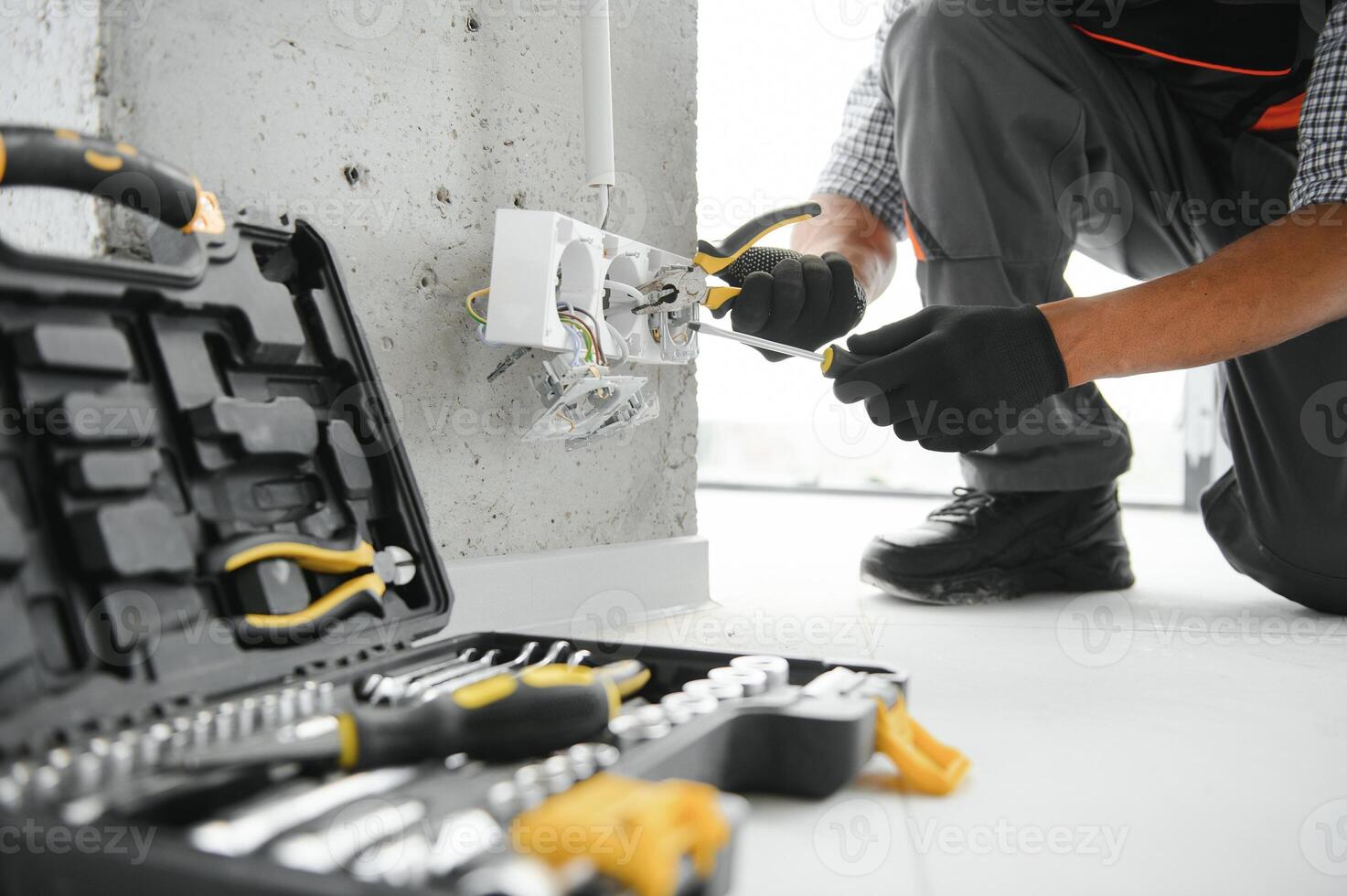 An African electrician installs electrical outlets at a construction site photo