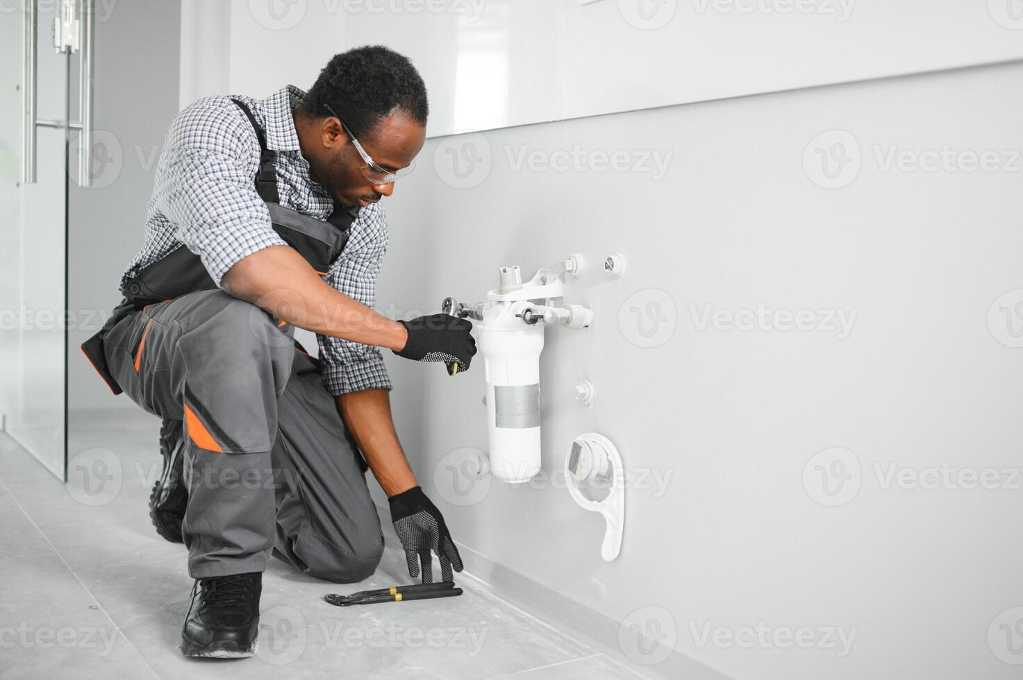 African american plumber change the water filter. photo