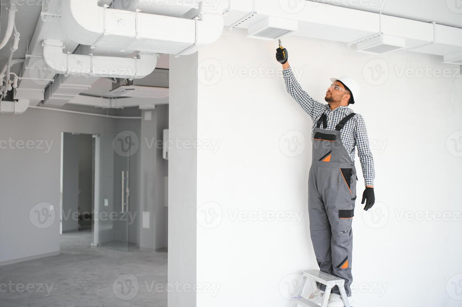 hvac indian worker install ducted pipe system for ventilation and air conditioning. copy space photo