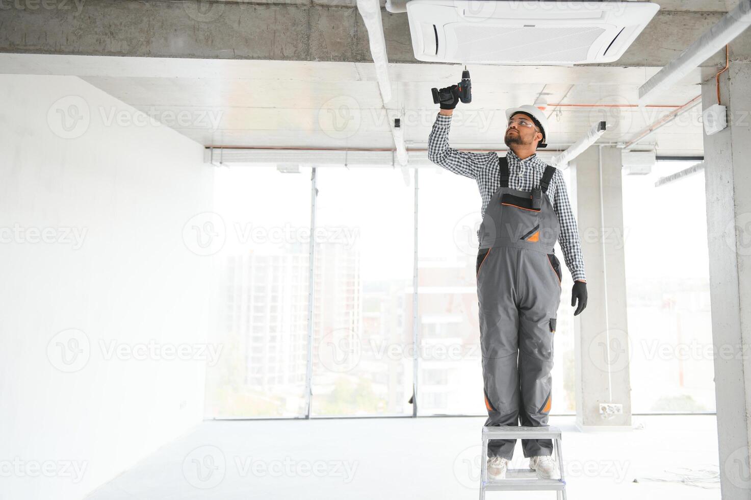 Professional technician maintaining modern air conditioner indoors. Space for text photo