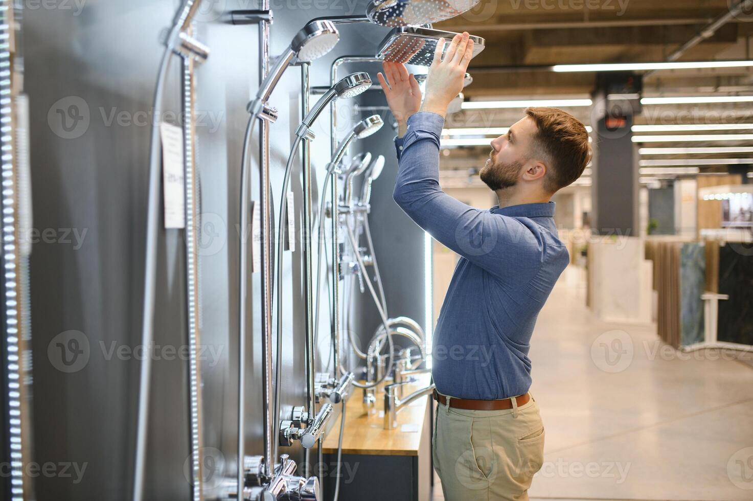 Selects a shower faucet. Man chooses a products in a sanitary ware store photo