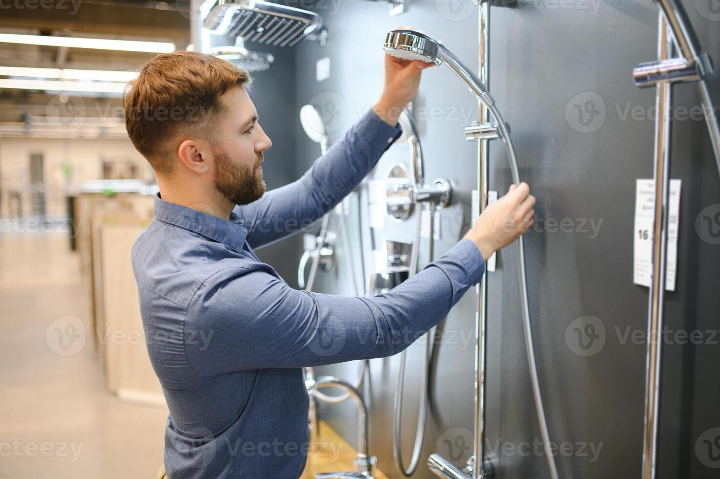 Selects a shower faucet. Man chooses a products in a sanitary ware store photo