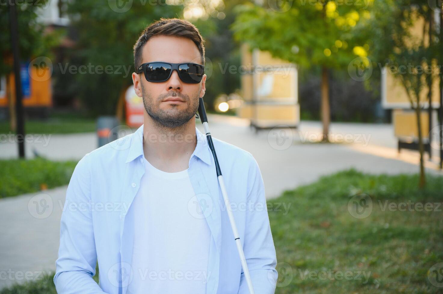 Portrait of a young, handsome blind man walking in the city. The concept of limited physical capabilities. photo