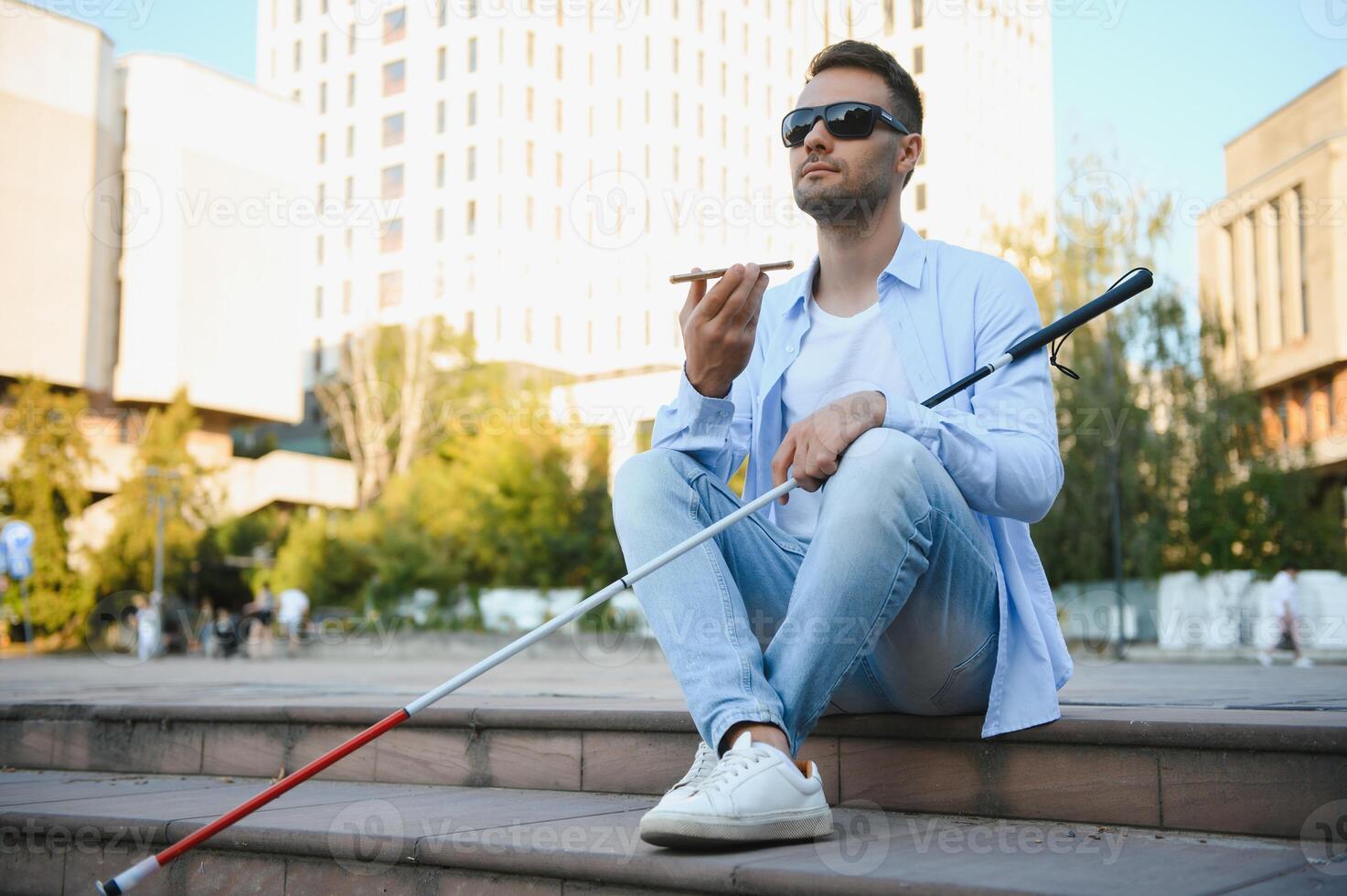 Portrait of a young, handsome blind man walking in the city. The concept of limited physical capabilities. photo