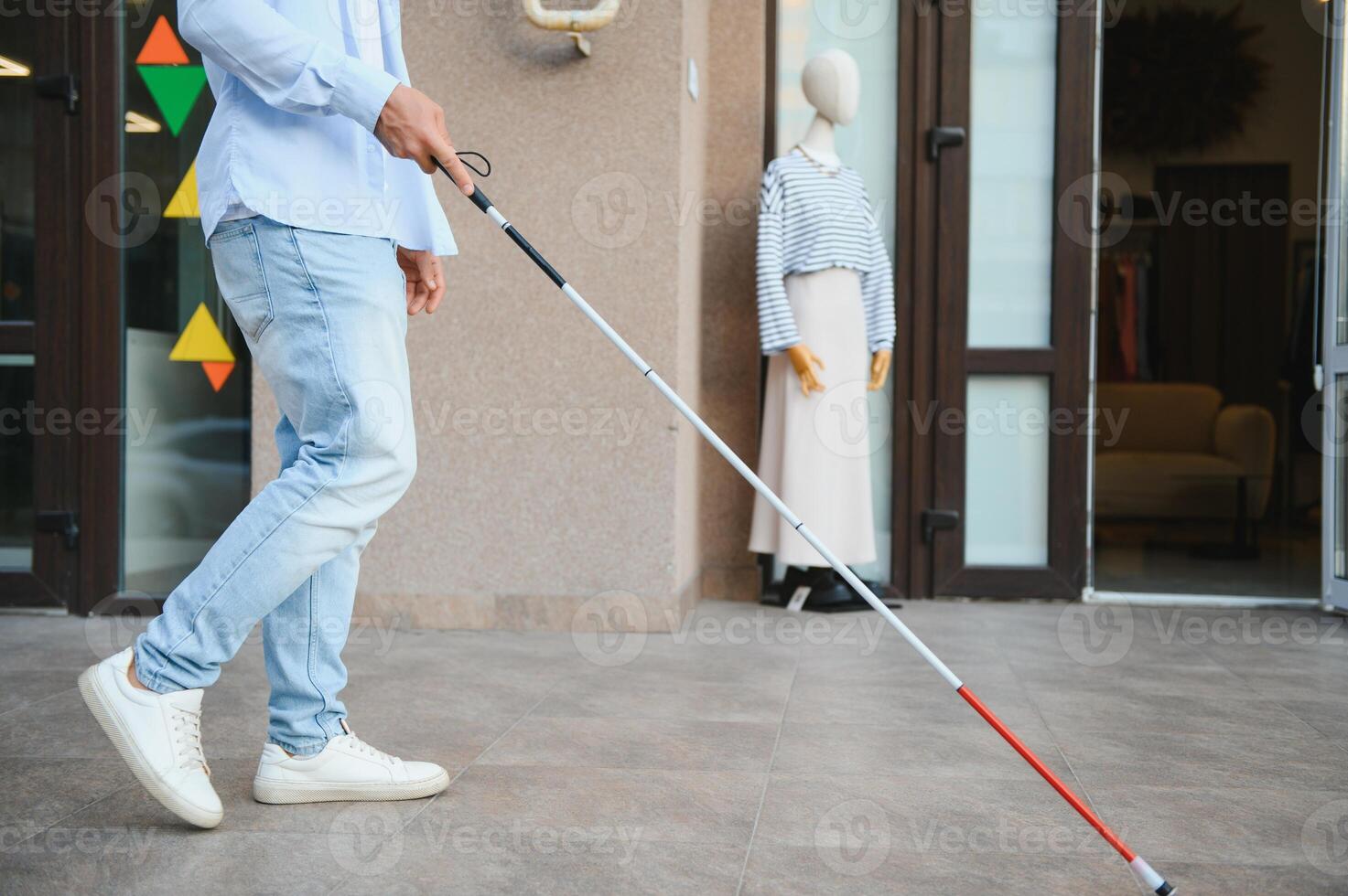 Young handsome blinded man walking with stick in town photo