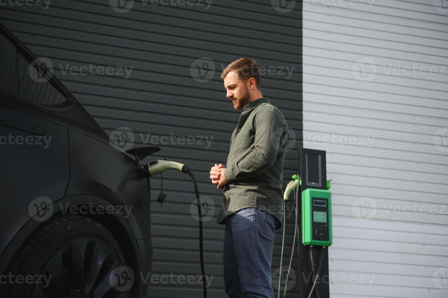 Man charging electric car by the house photo