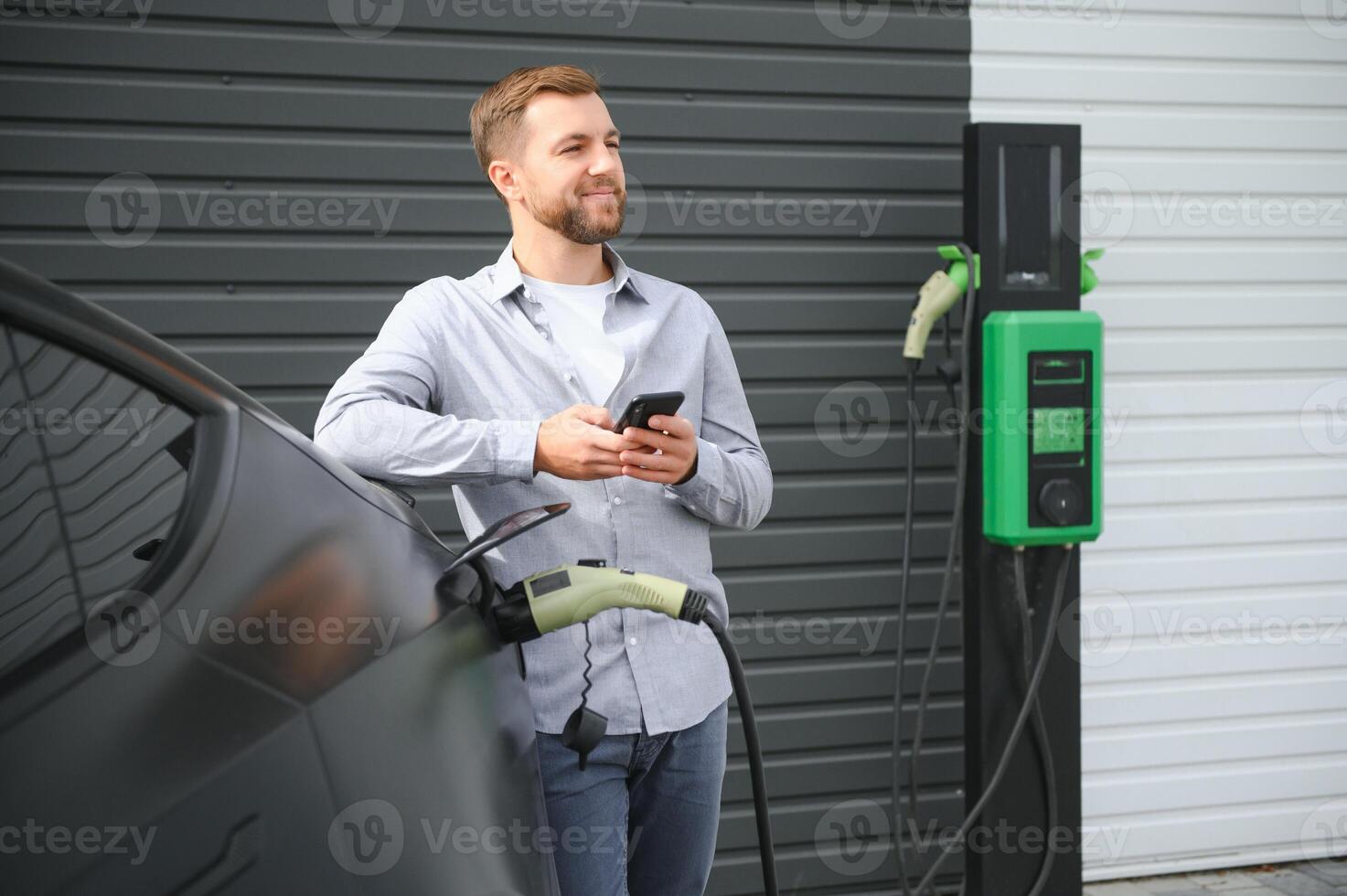 Man charging electric car by the house photo
