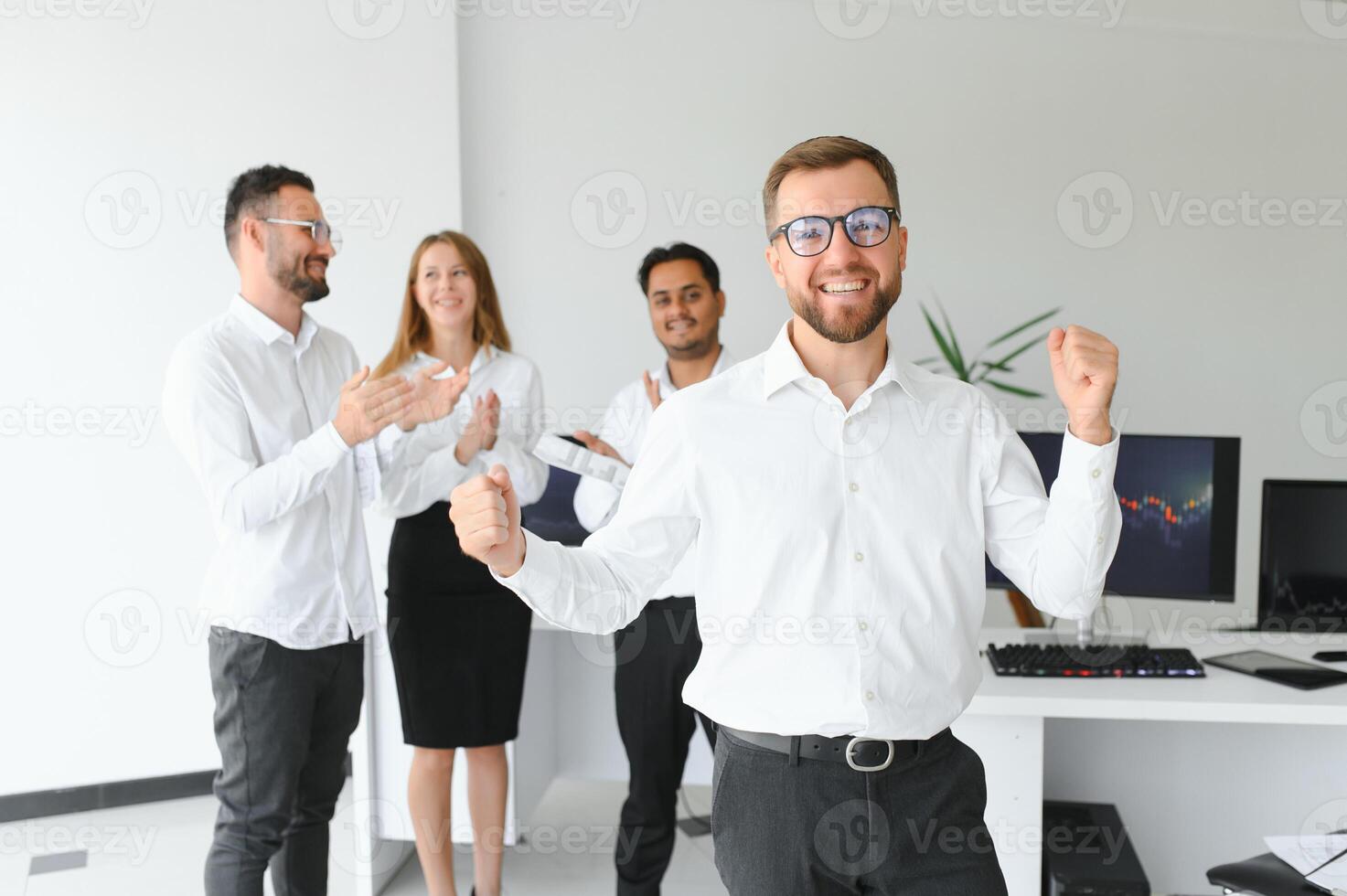Team leader stands with coworkers in background photo
