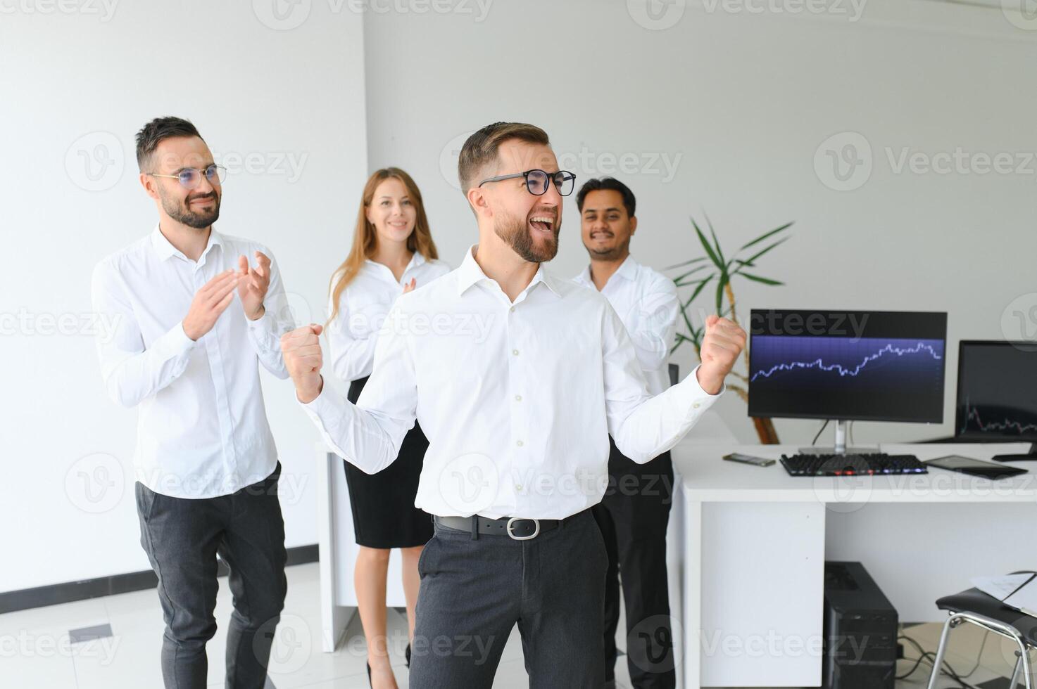 Team leader stands with coworkers in background photo