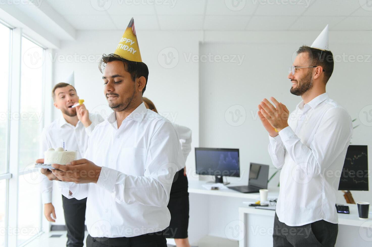 happy business team with birthday cake and gifts greeting indian male colleague at office party photo
