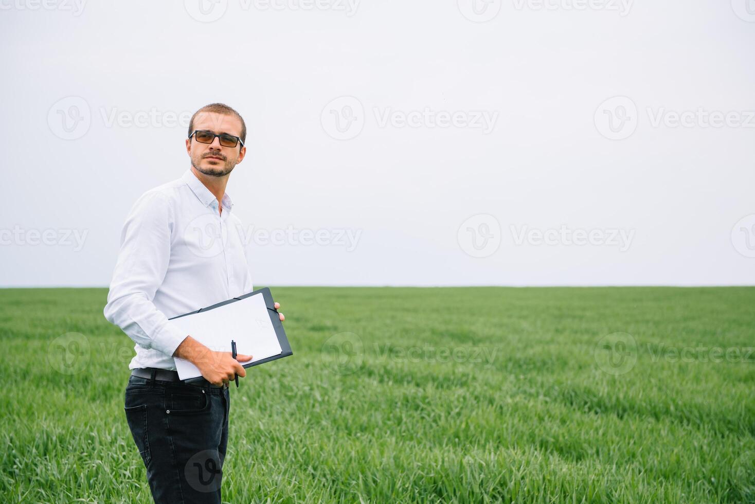 Young agronomist holds tablet touch pad computer in green wheat field. Agribusiness concept. agricultural engineer standing in a wheat field with a tablet in summer photo