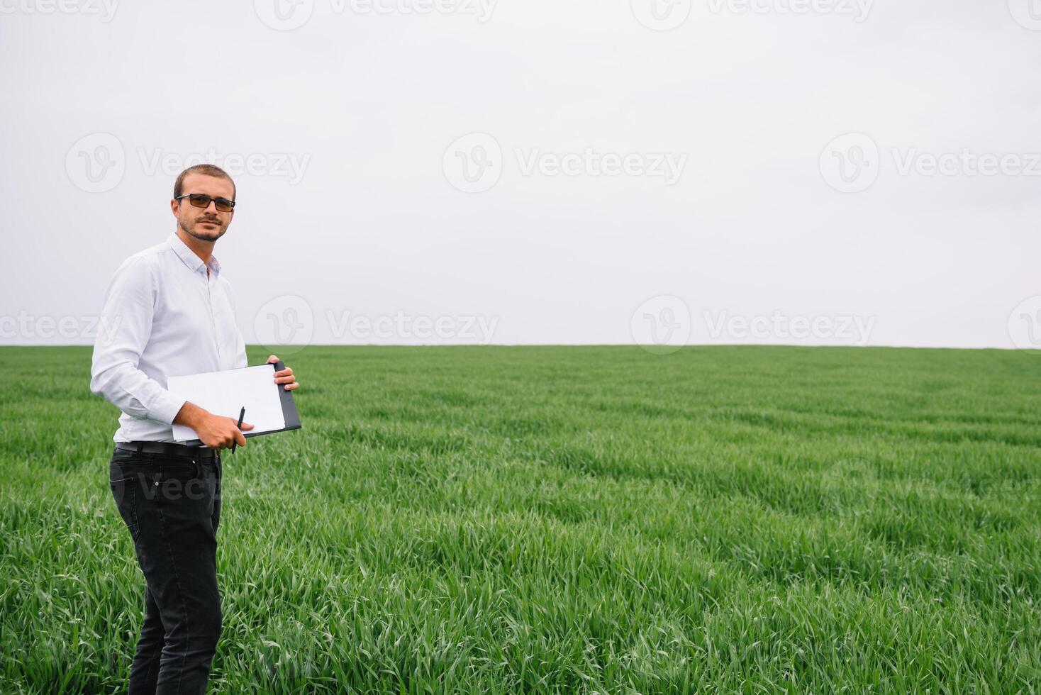 Young agronomist holds tablet touch pad computer in green wheat field. Agribusiness concept. agricultural engineer standing in a wheat field with a tablet in summer photo