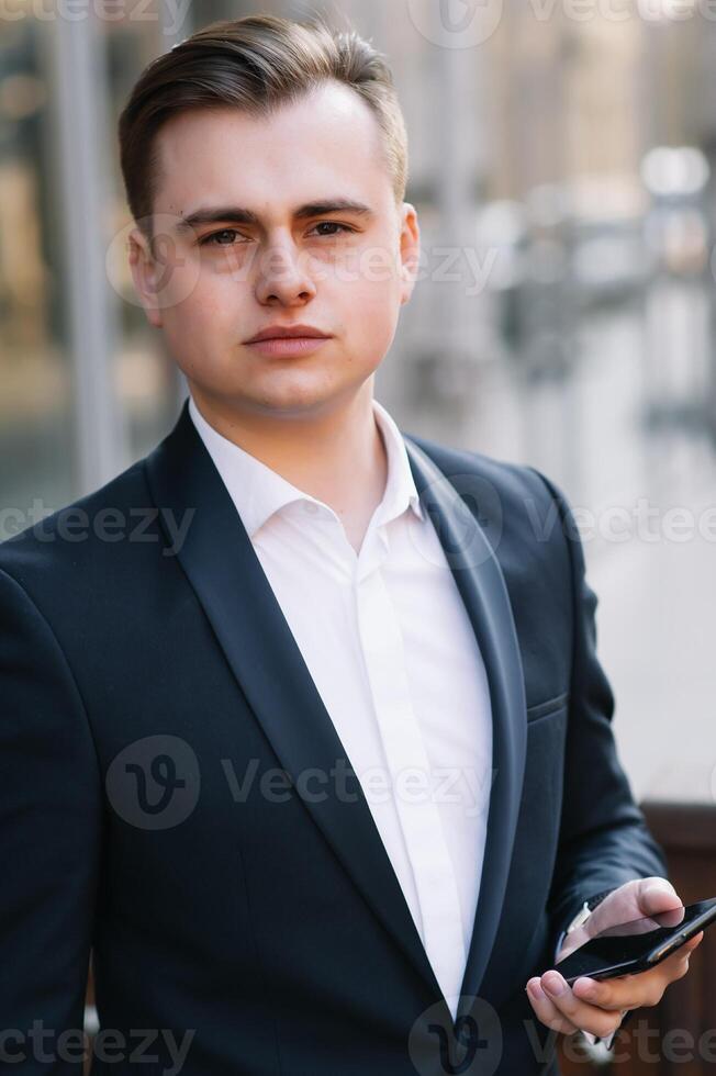 Young business man with documents and mobile phone near of modern building. photo
