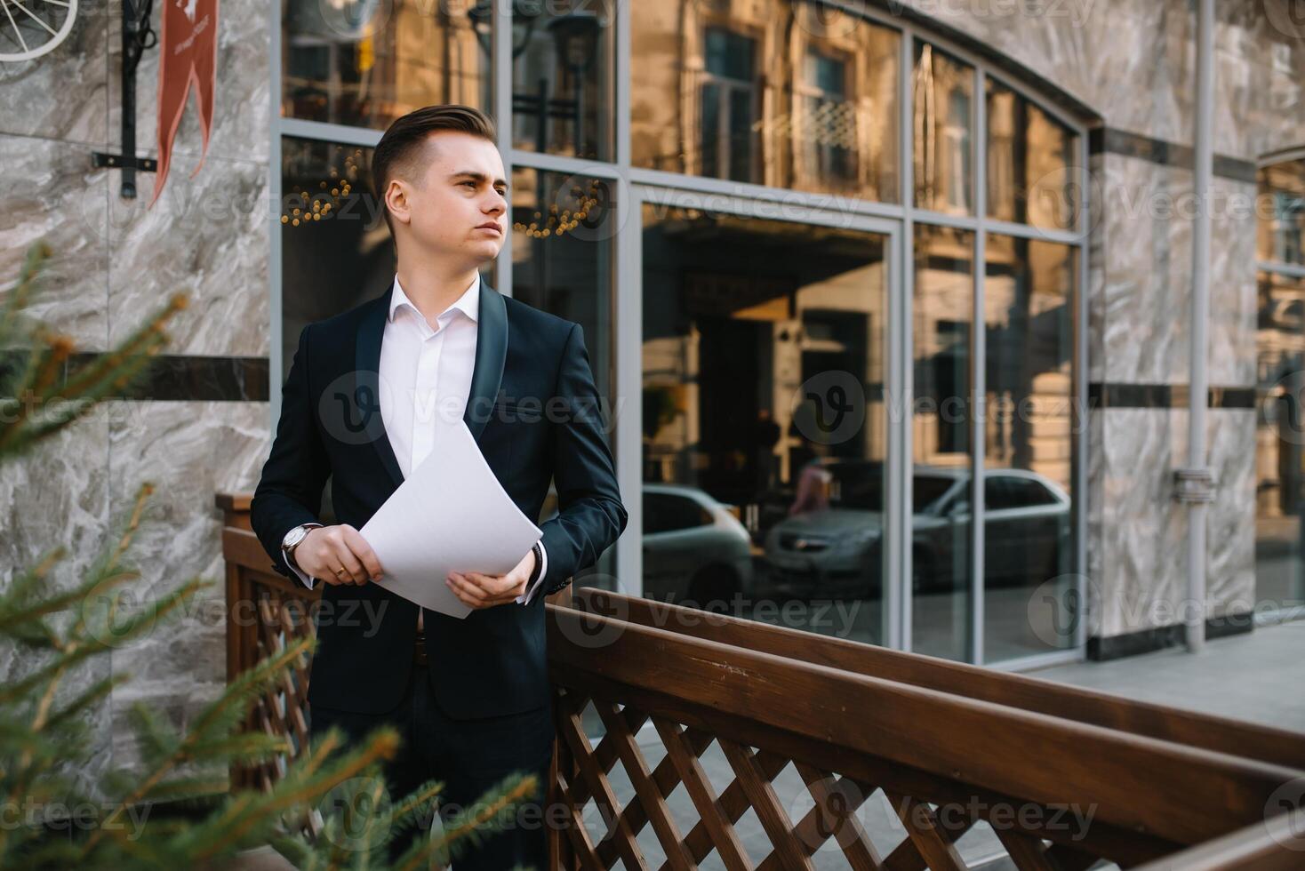 Young business man with documents and mobile phone near of modern building. photo