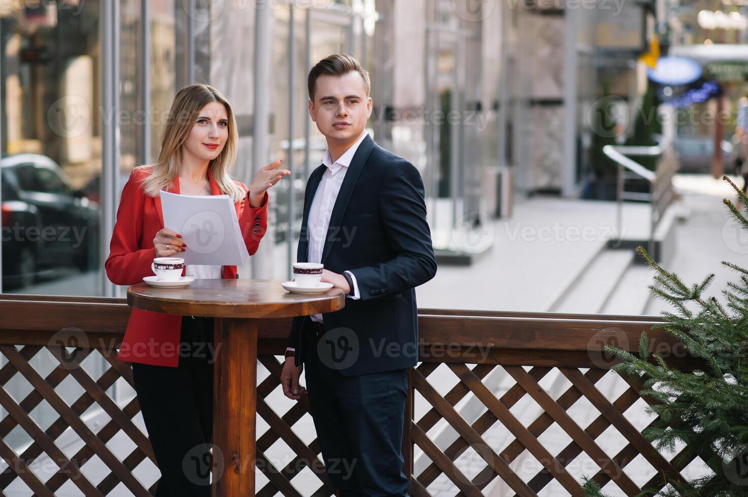 Preparation for meeting. Two young business people standing outside on the city street holding documents looking at each other smiling happy bottom view close-up photo