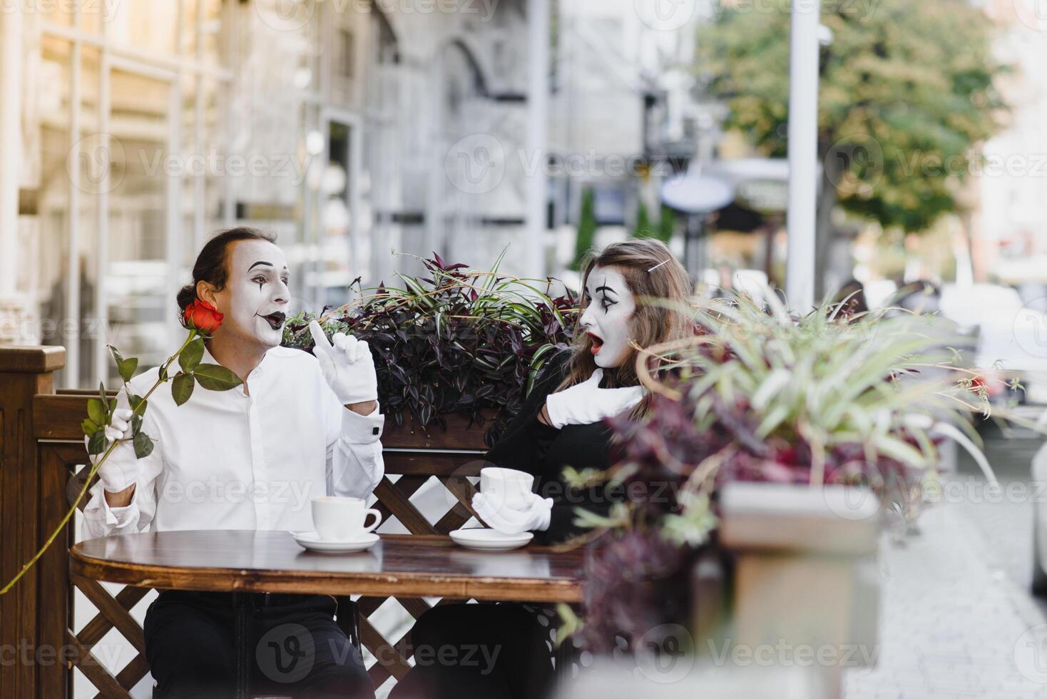 mime guy and girl in cafe drinking coffee. Mime in front of Paris cafe acting like drinking tea or coffee. photo